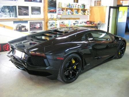 A black lamborghini aventador is parked in a garage