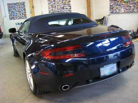 A black sports car with a convertible top is parked in a garage.