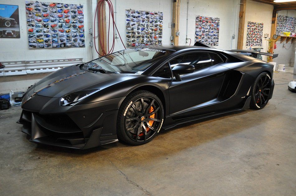 A black lamborghini aventador is parked in a garage.