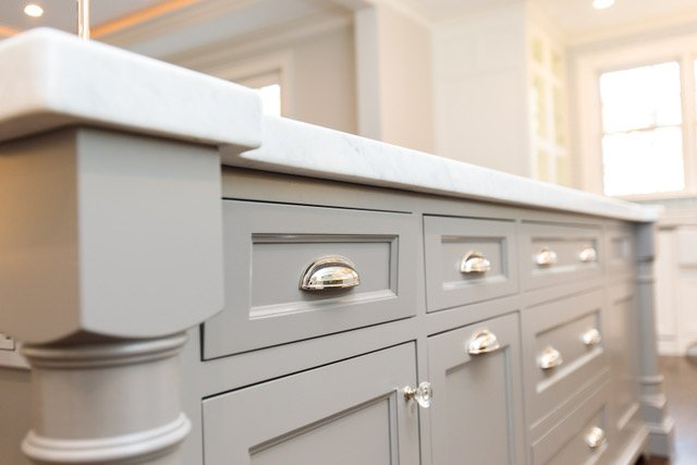 A kitchen with gray cabinets and a white counter top