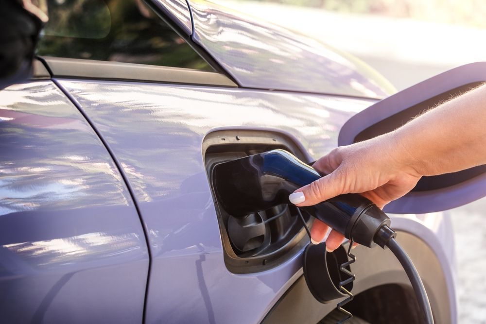 A woman is charging an electric car with a charger.