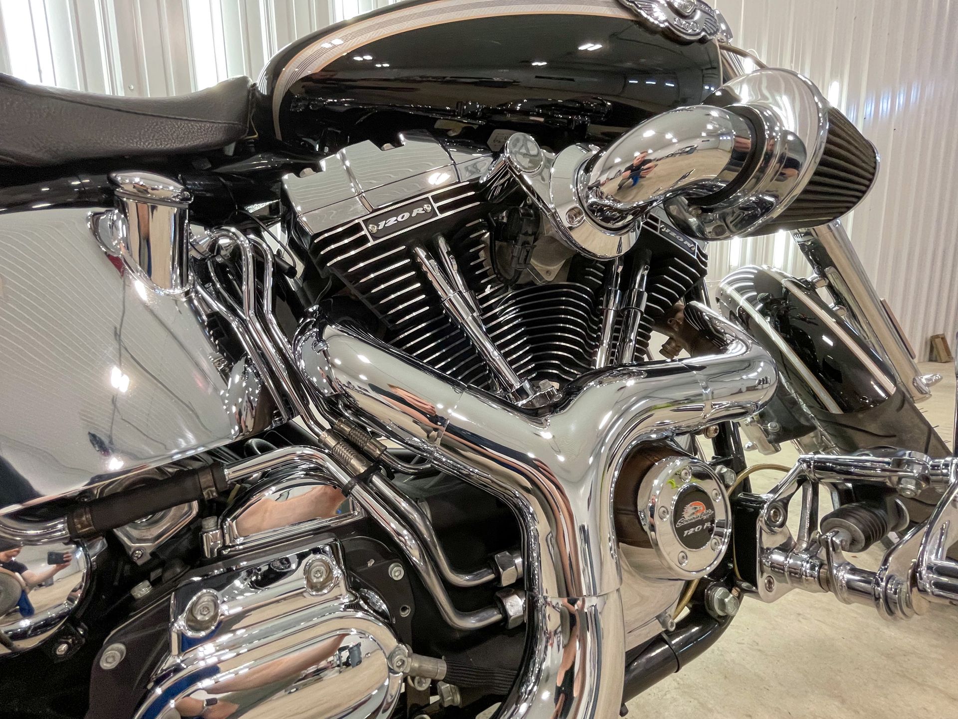 A close-up view of a black motorcycle engine with prominent chrome exhaust pipes and a custom air intake system.