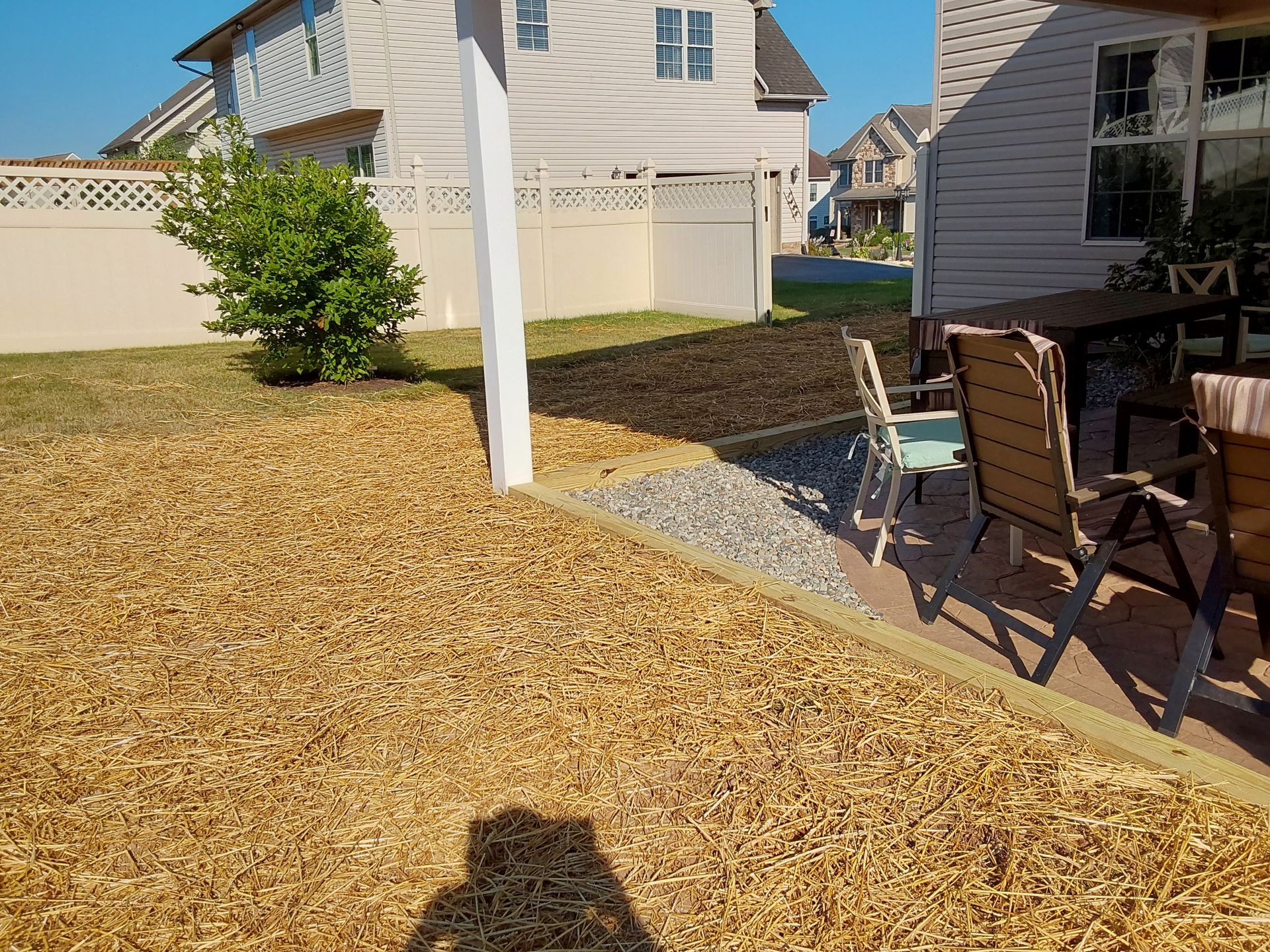 a backyard with a table and chairs and a white fence