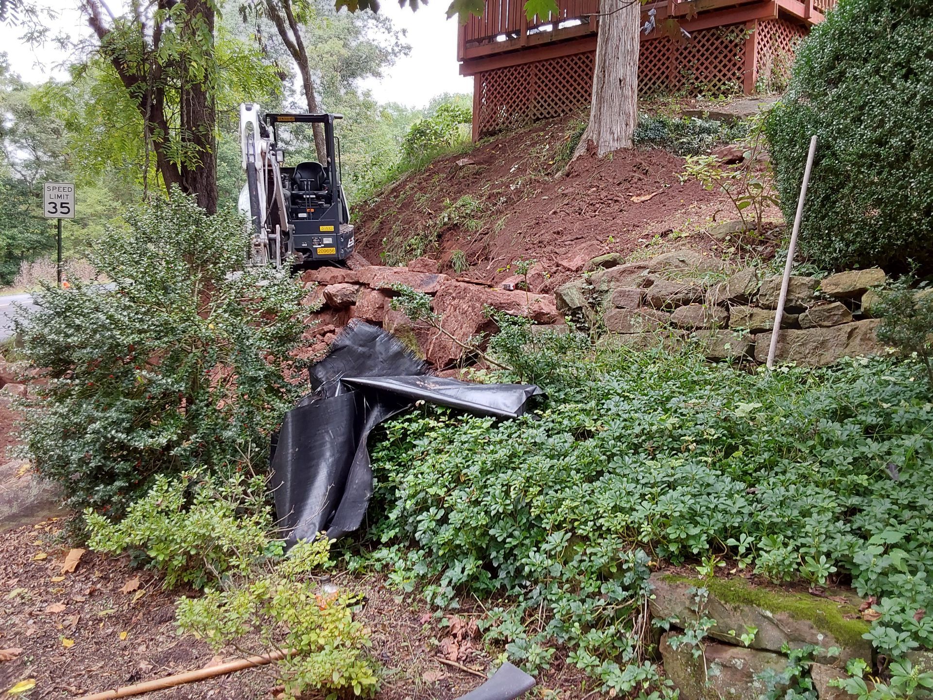 a bulldozer is working on a rock wall in a garden