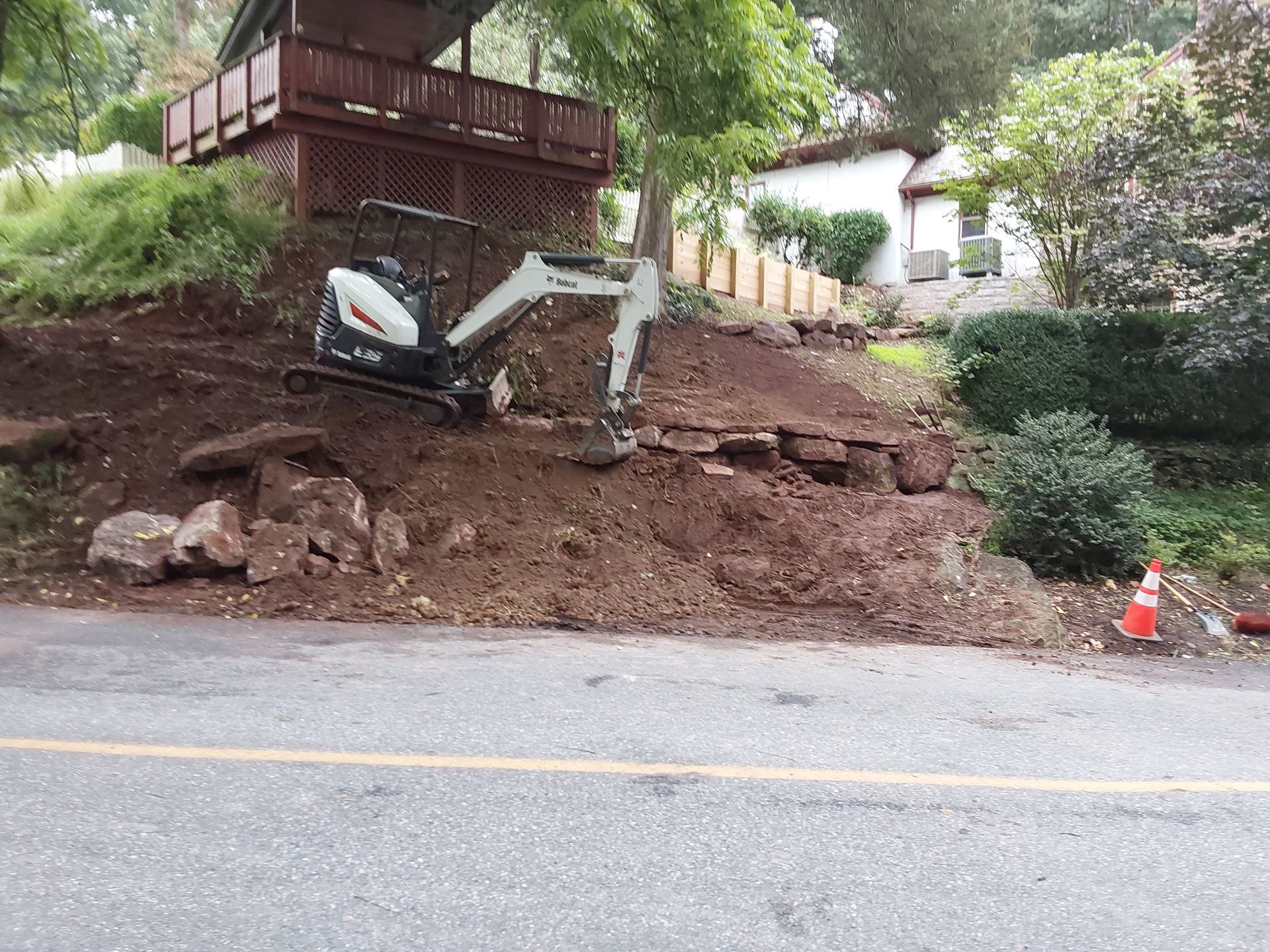 a small excavator is working on a dirt hill in front of a house