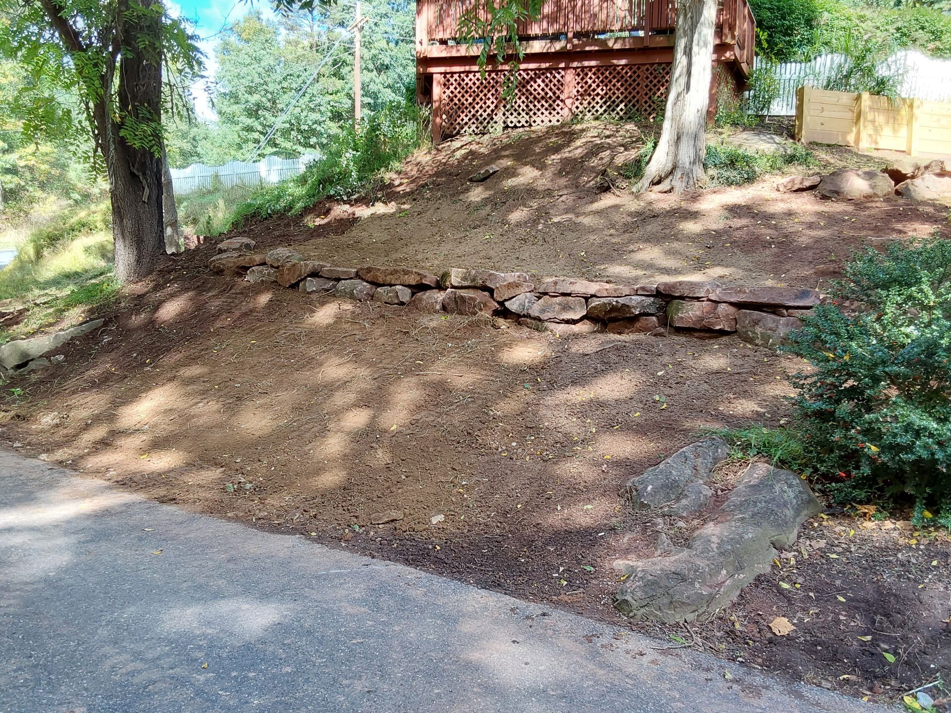 a dirt hill with a stone wall and a house in the background