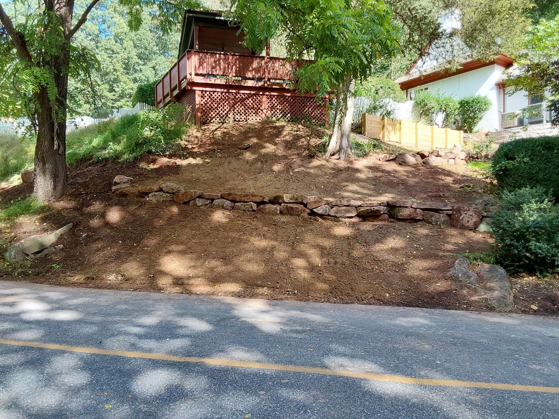 a house is sitting on top of a hill next to a road