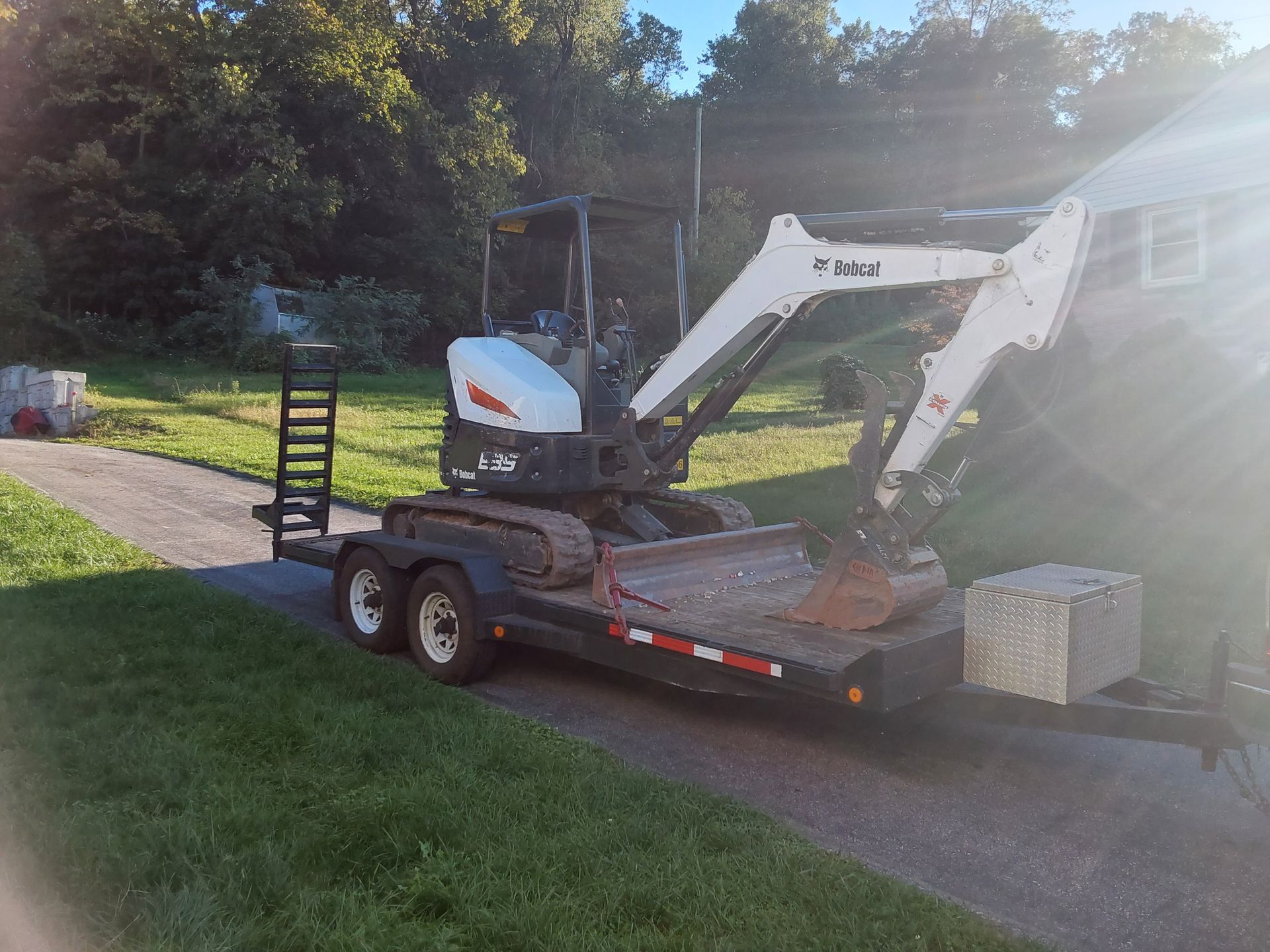 a bobcat excavator is parked on a trailer in a driveway