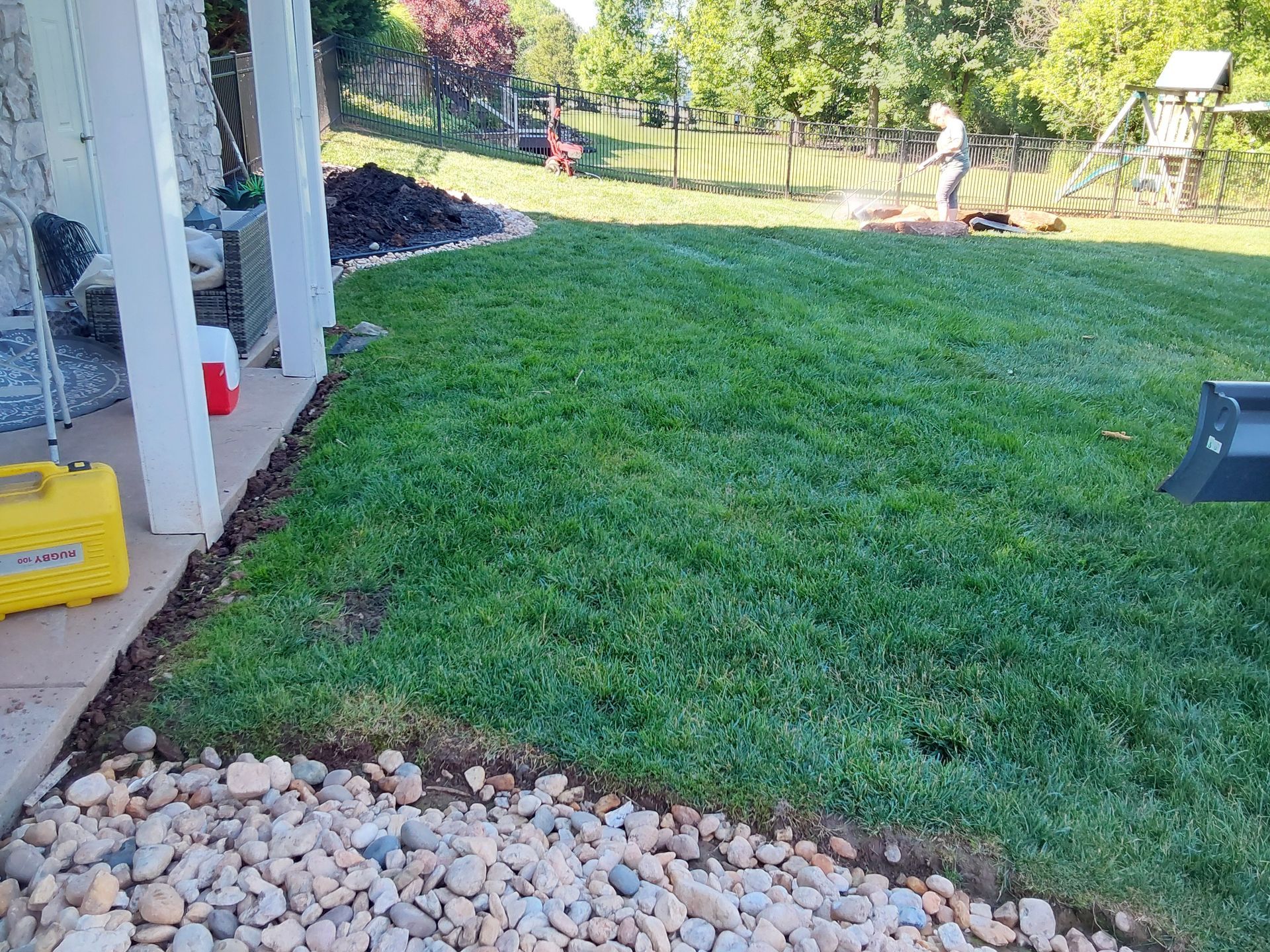 a man is mowing a lush green lawn in a backyard