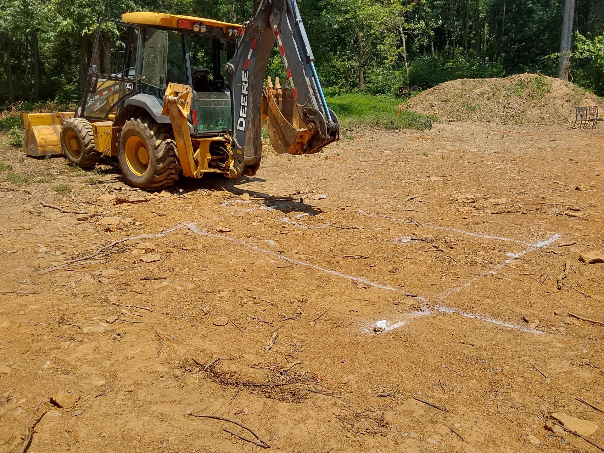 a yellow backhoe is sitting in the middle of a dirt field