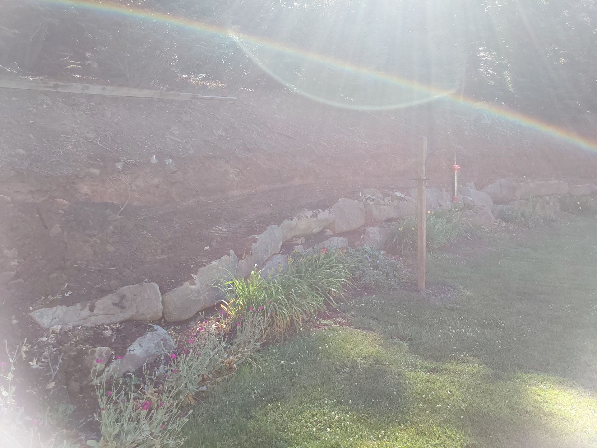 a rainbow is visible in the sky over a stone wall
