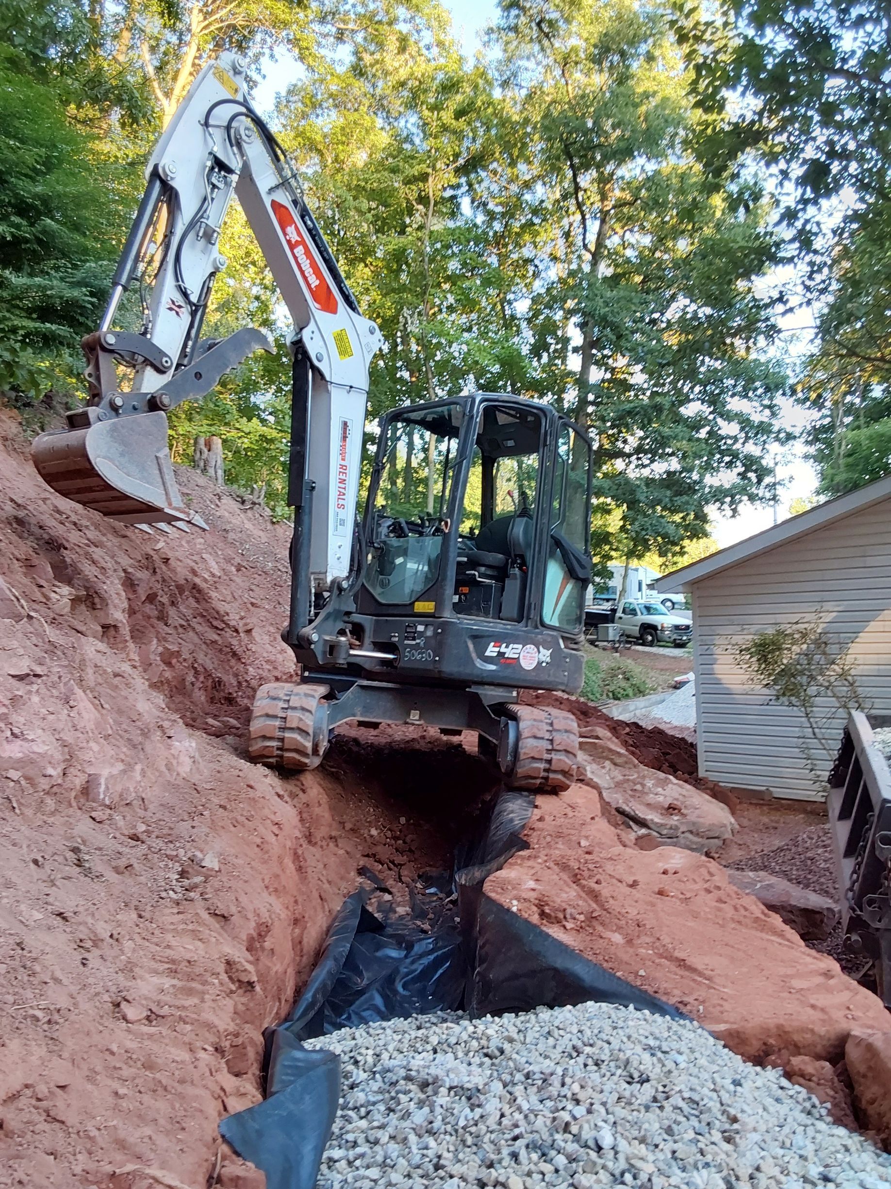 a small excavator is digging a hole in the ground next to a house
