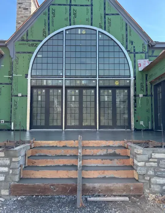 Green building entrance with arched glass doors and steps leading up from the sidewalk