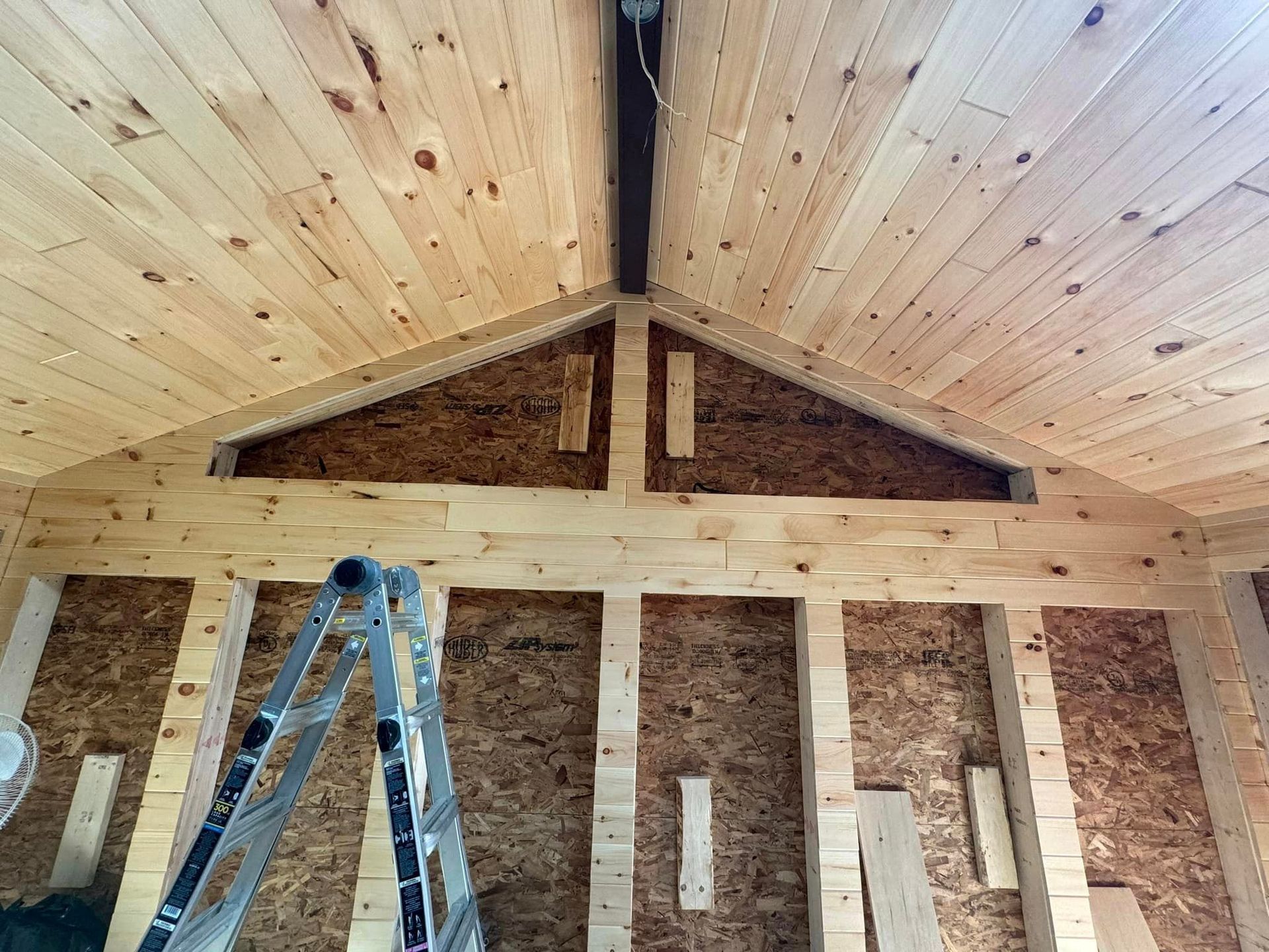 A ladder is sitting in a room with a wooden ceiling.