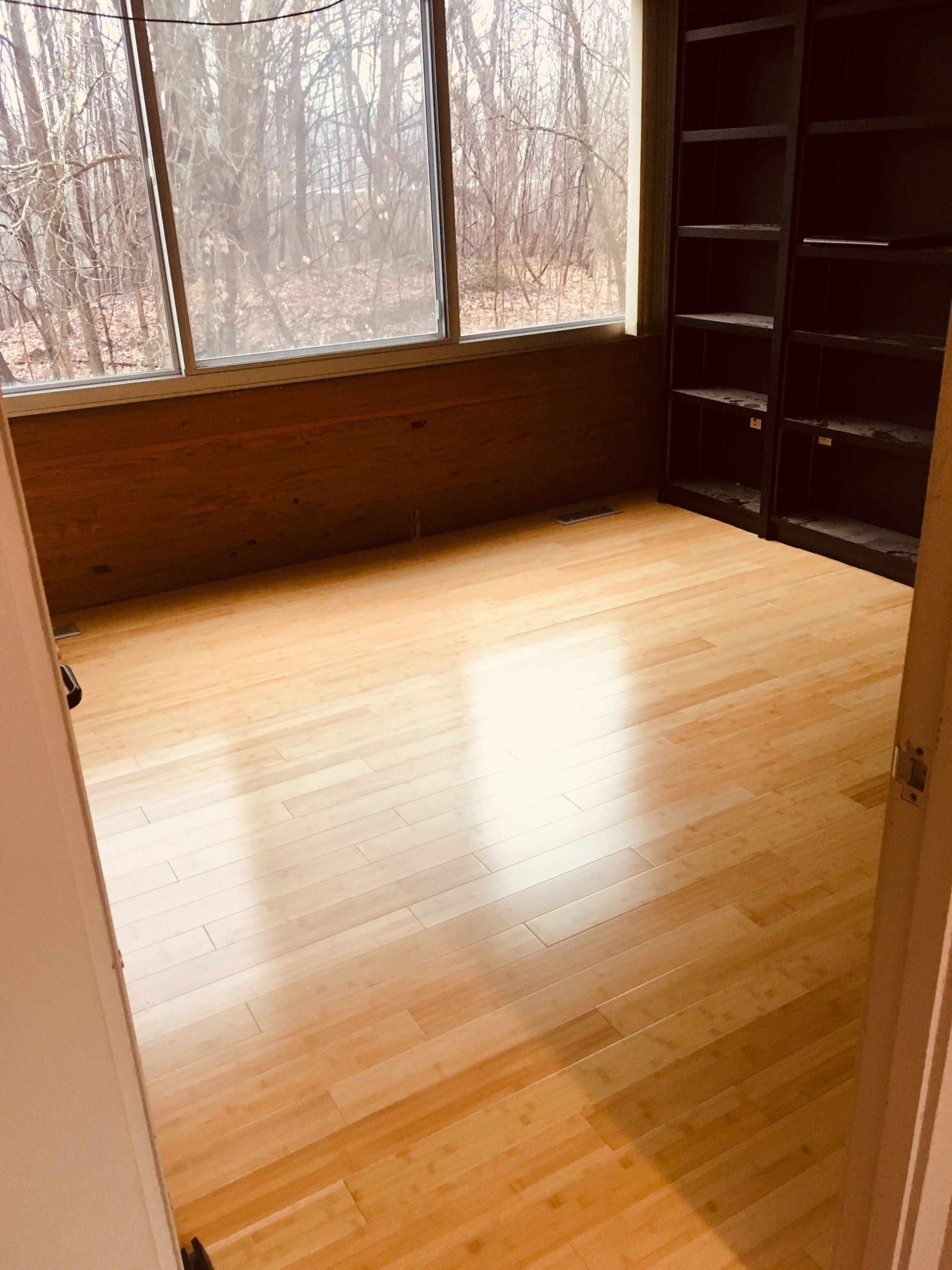 An empty room with hardwood floors and a large window.