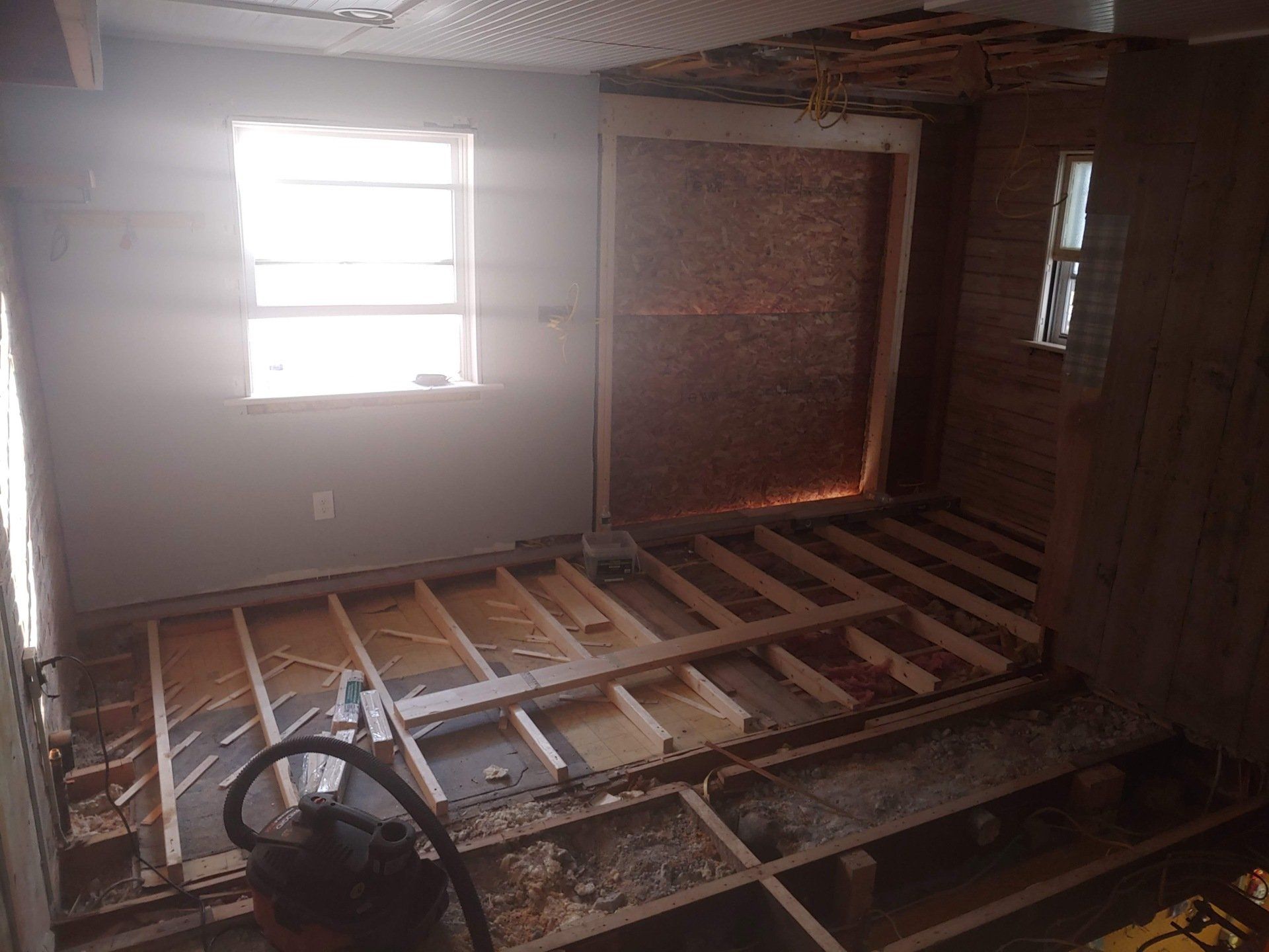 A room with a vacuum cleaner on the floor and a window.