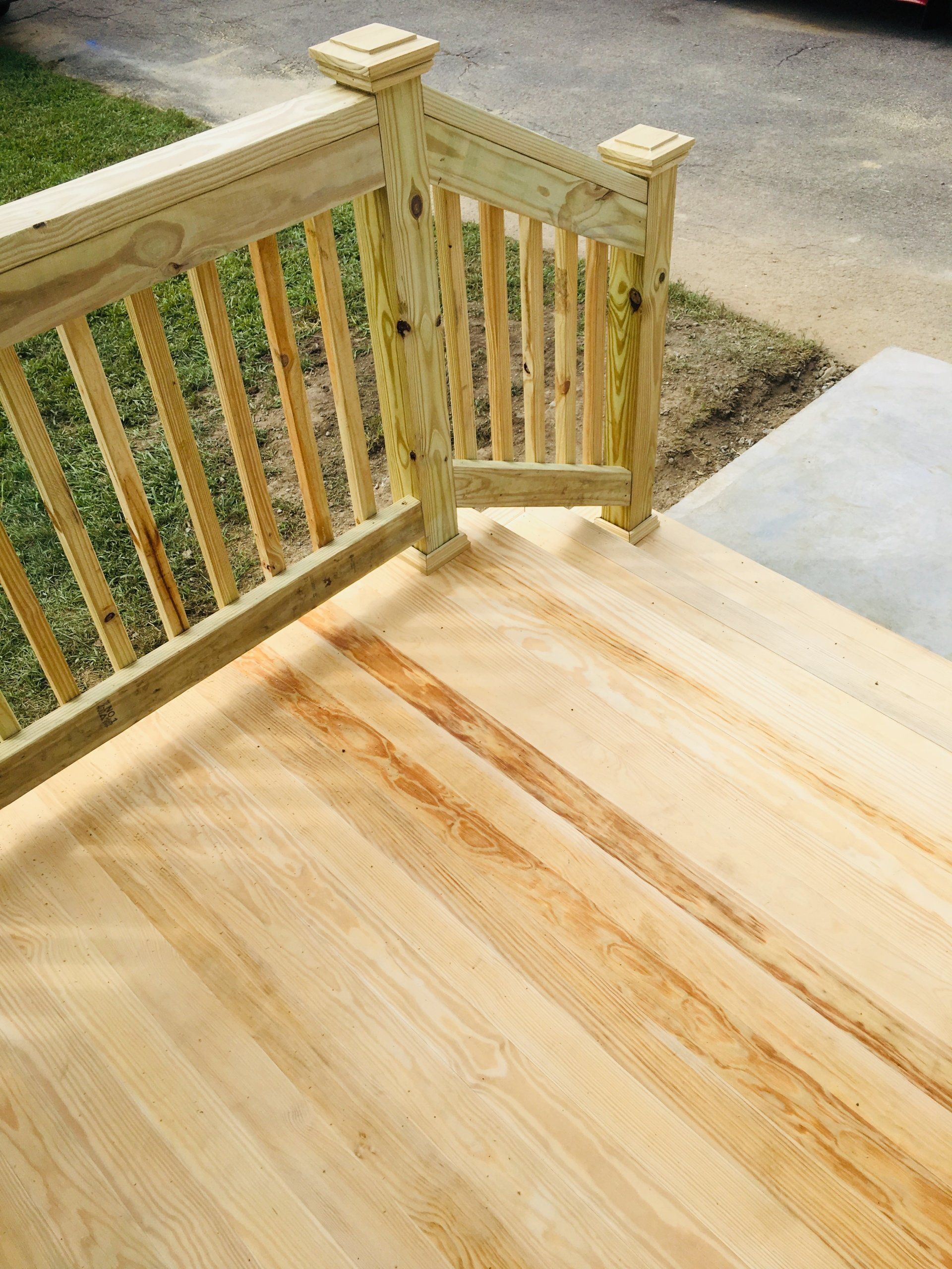 A wooden deck with a wooden railing and stairs