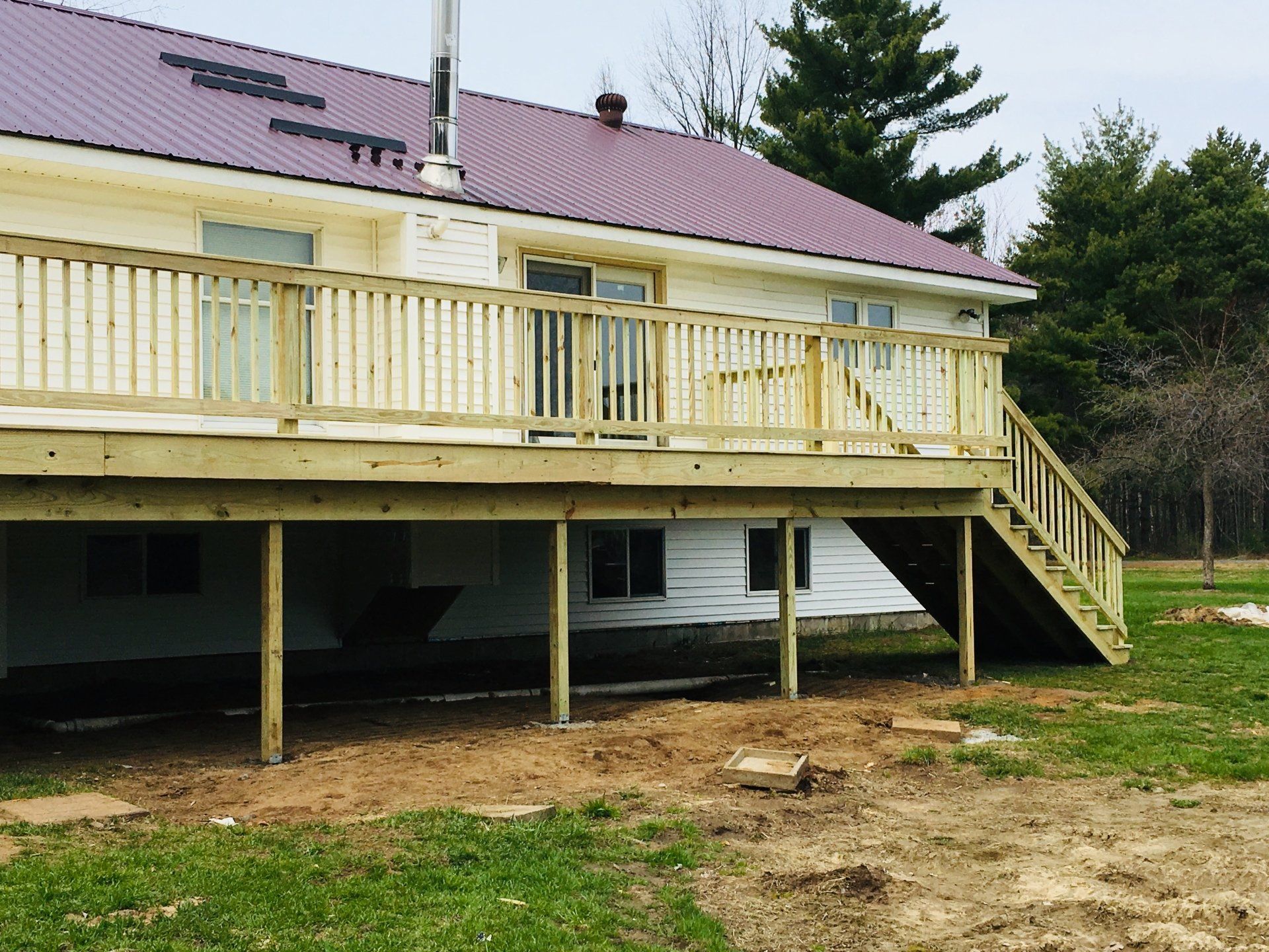 A white house with a purple roof and a wooden deck