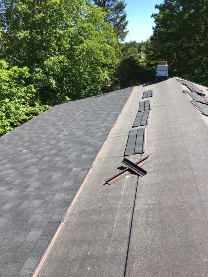 A roof with a lot of shingles on it and trees in the background.