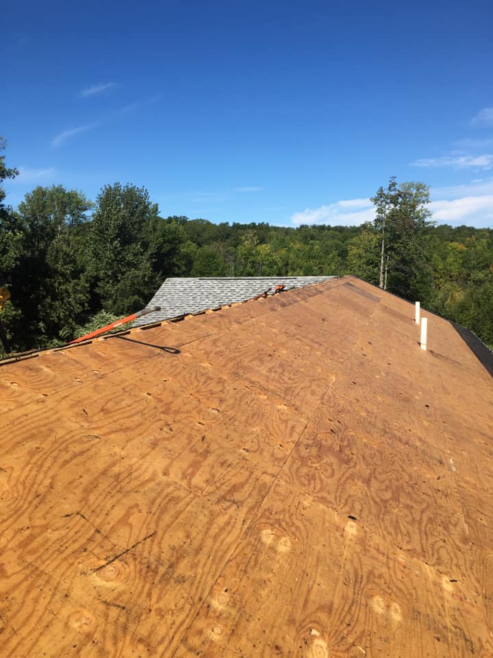 The roof of a house is covered in plywood and shingles.
