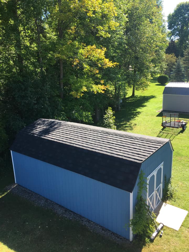 An aerial view of a blue barn with a black roof