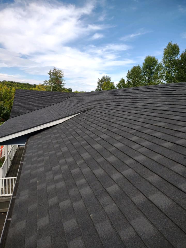 A house with a black roof and a blue sky in the background.