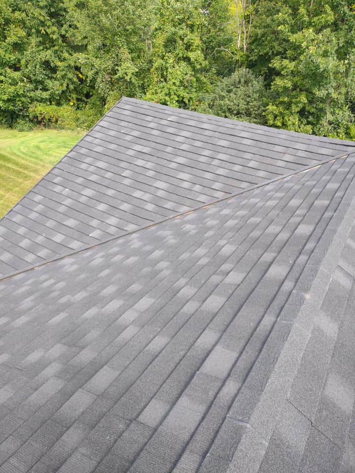 A roof with a lot of shingles on it is surrounded by trees.