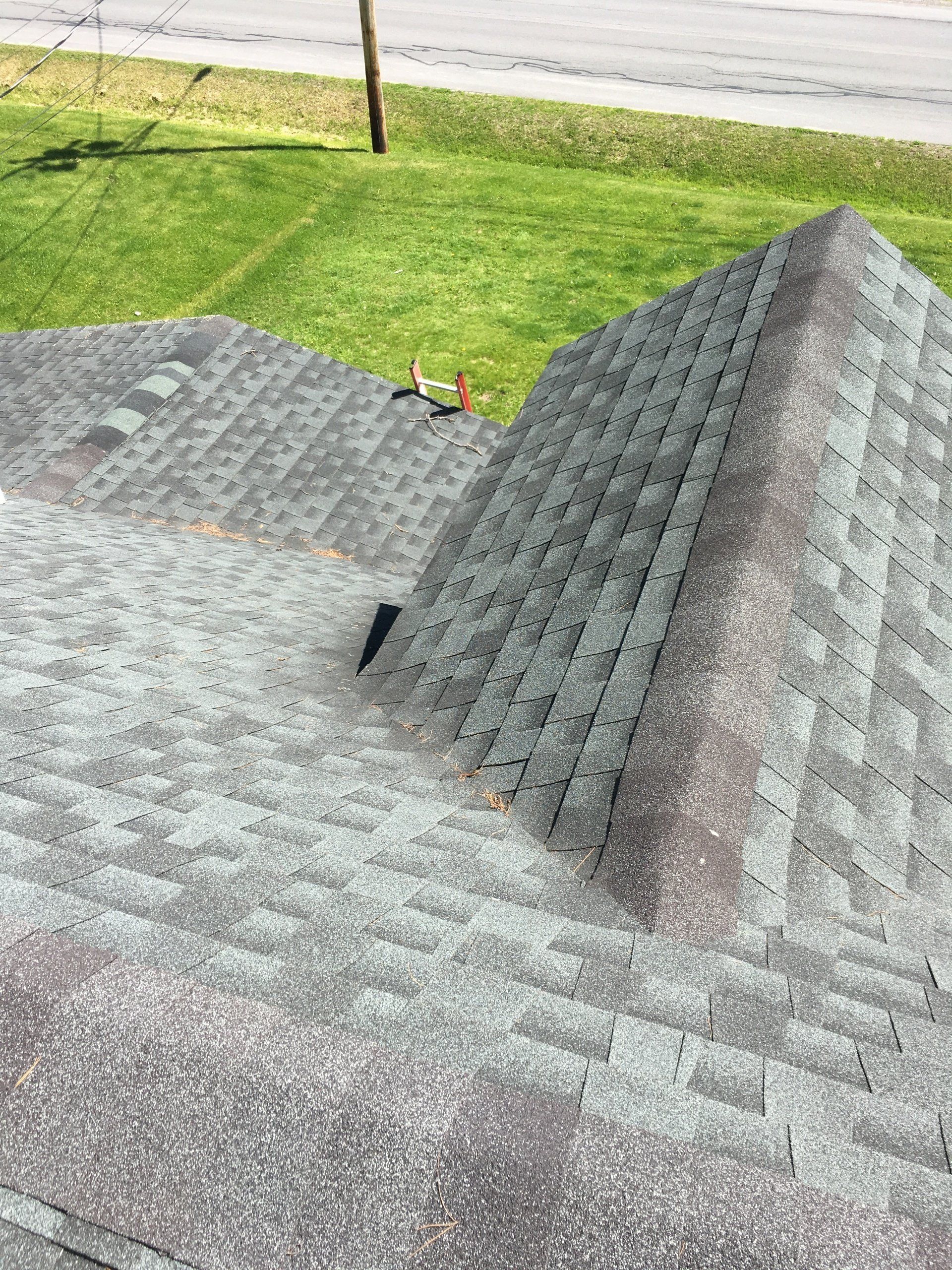 A roof with a lot of shingles on it is sitting on top of a lush green field.