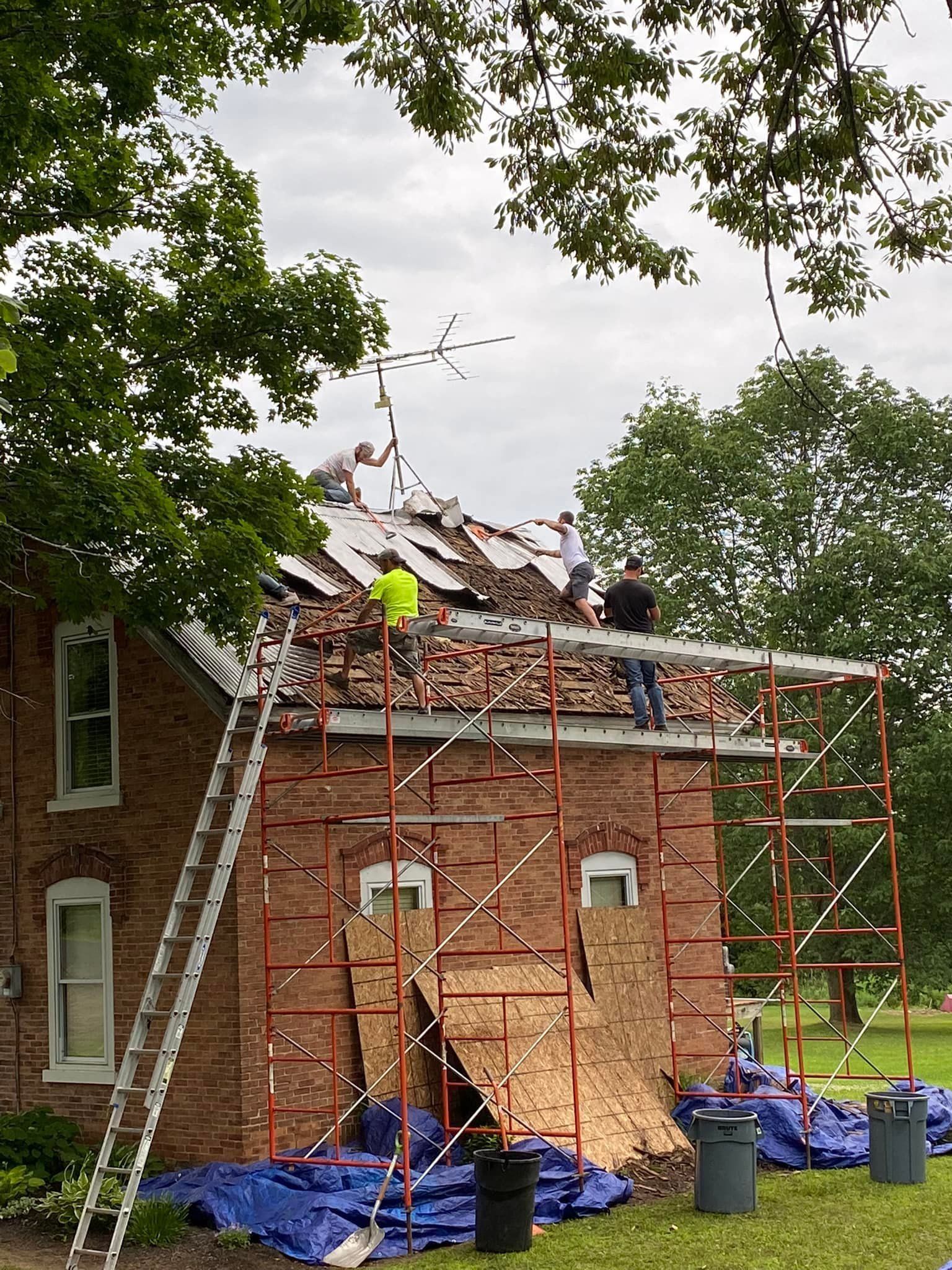 A group of people are working on the roof of a brick building.