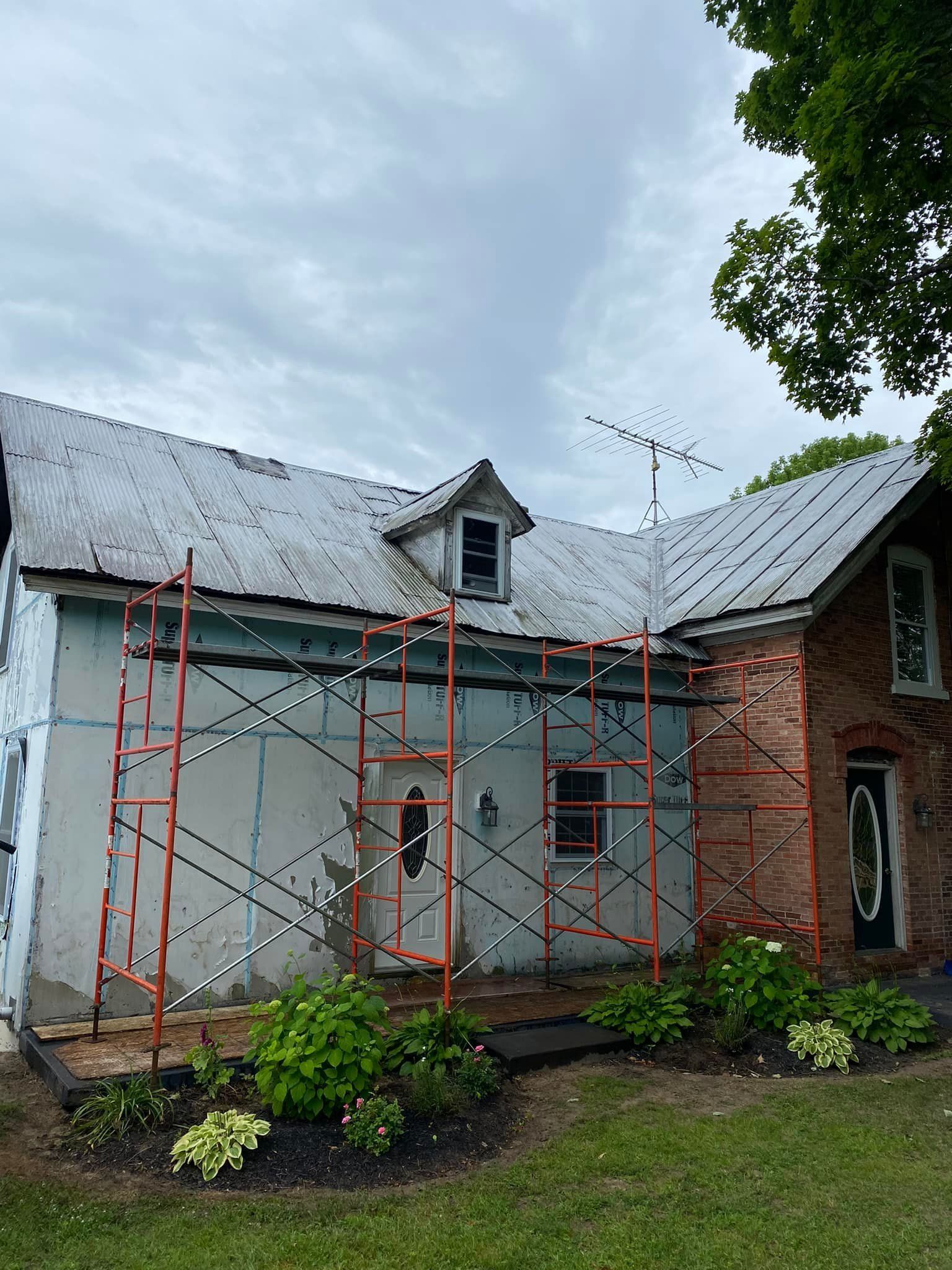 A house with scaffolding around it is being painted white.