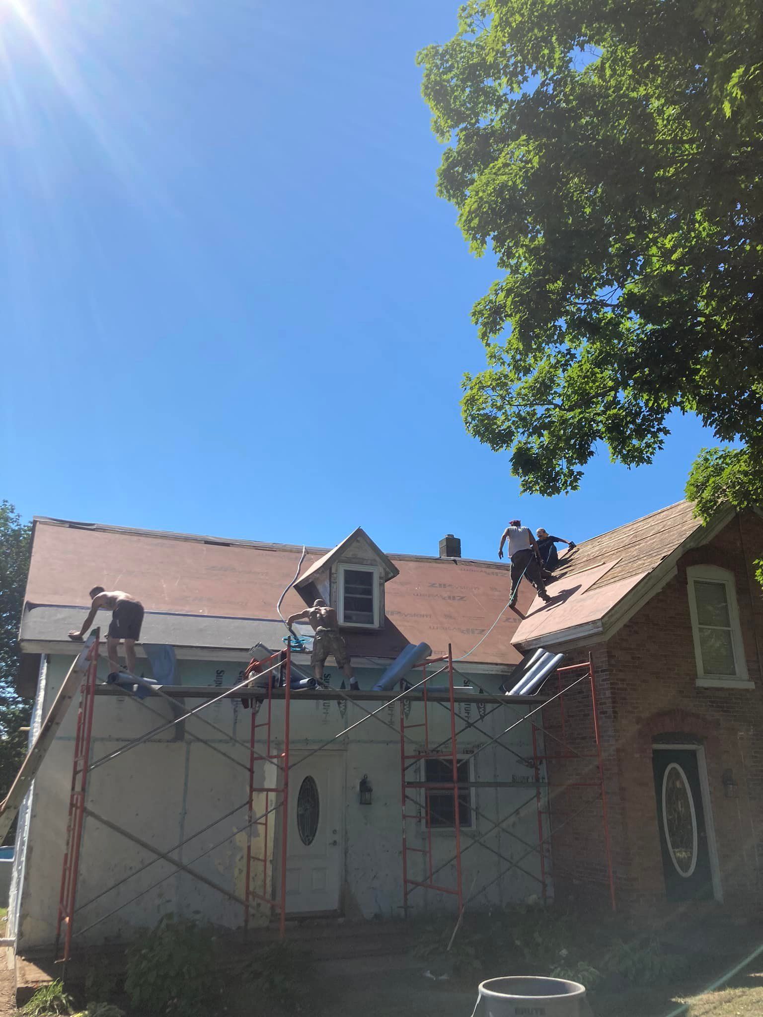 A group of people are working on the roof of a house.
