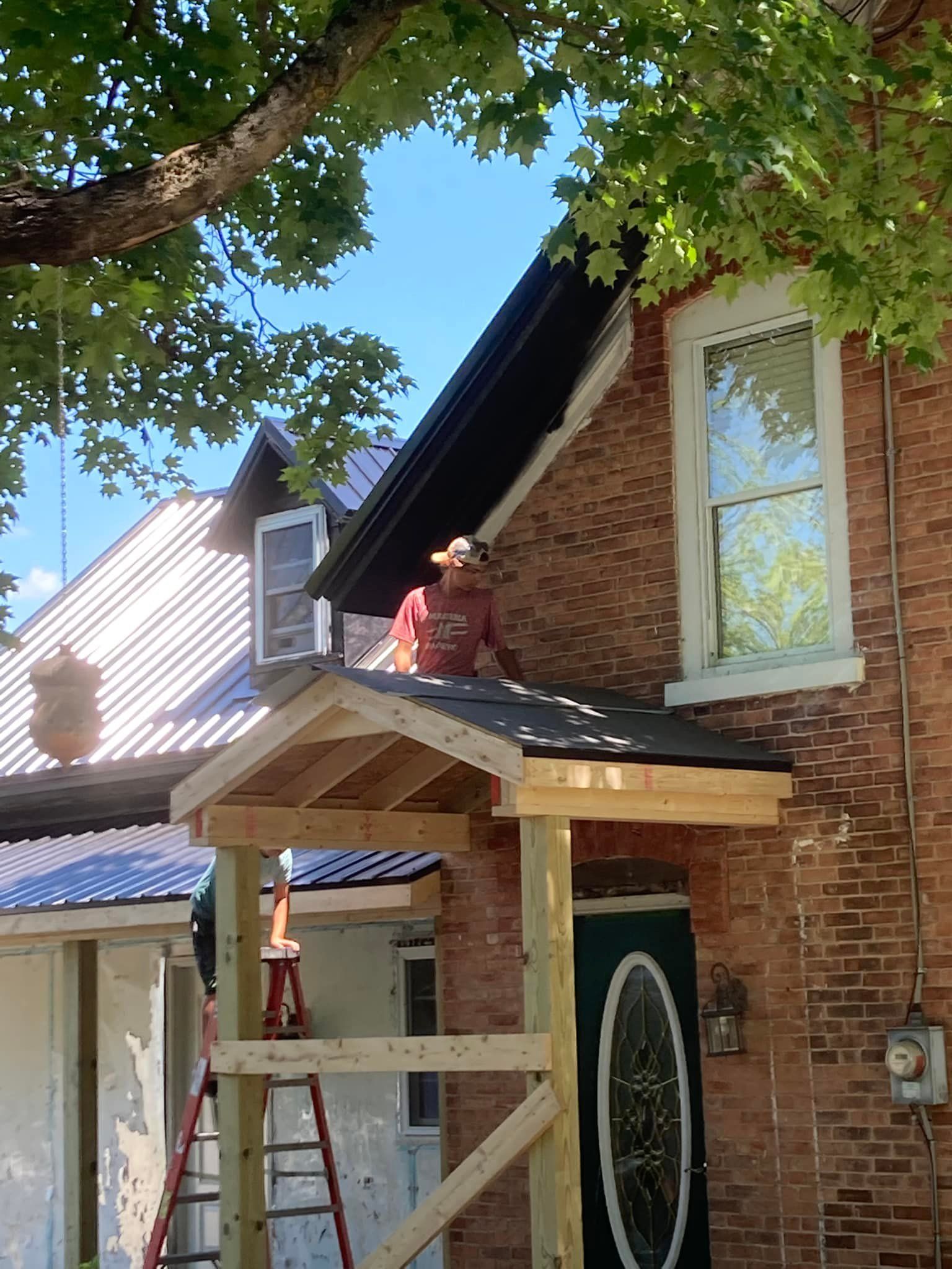 A man is standing on the roof of a brick house.