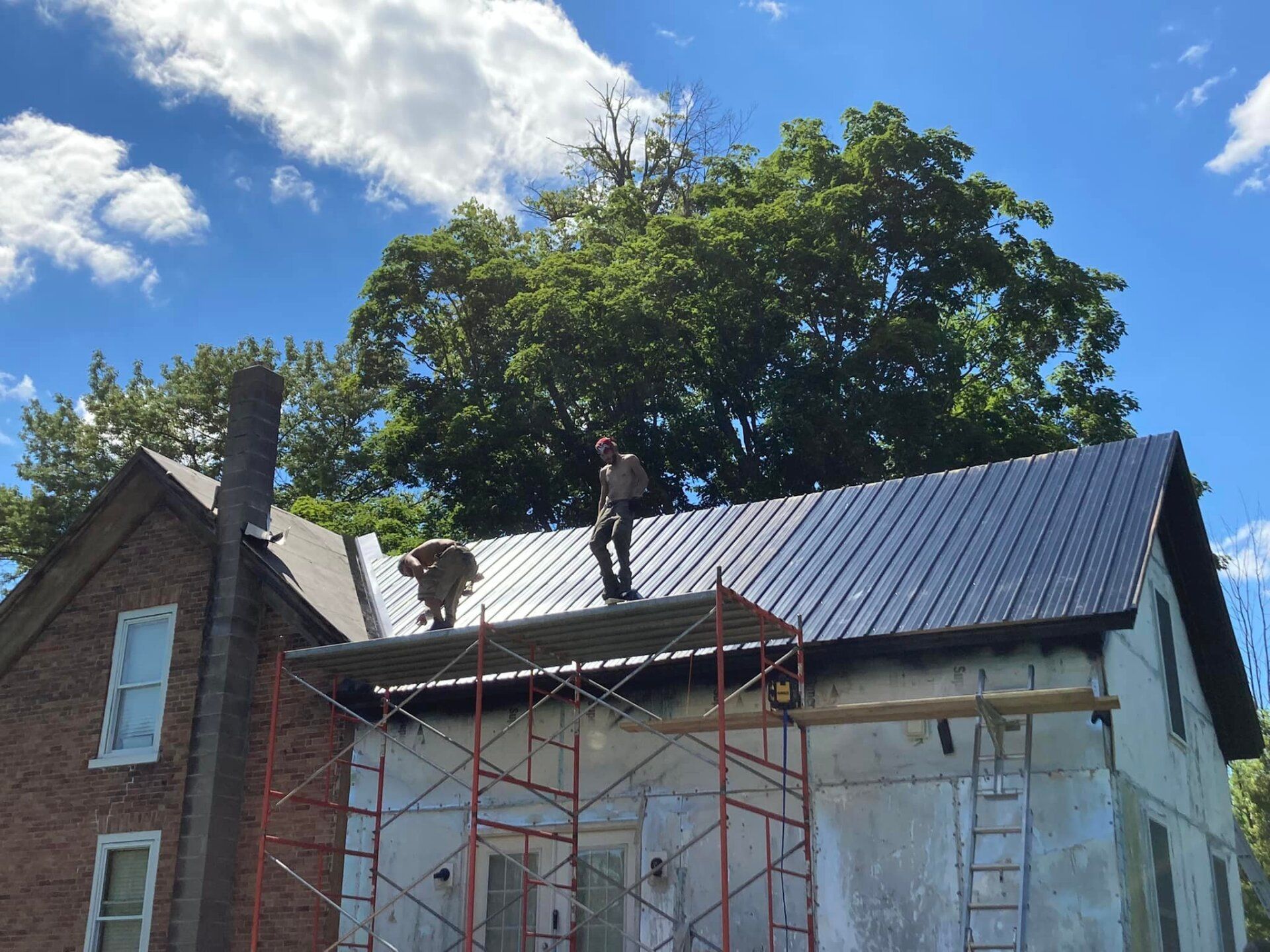 A group of people are working on the roof of a house.