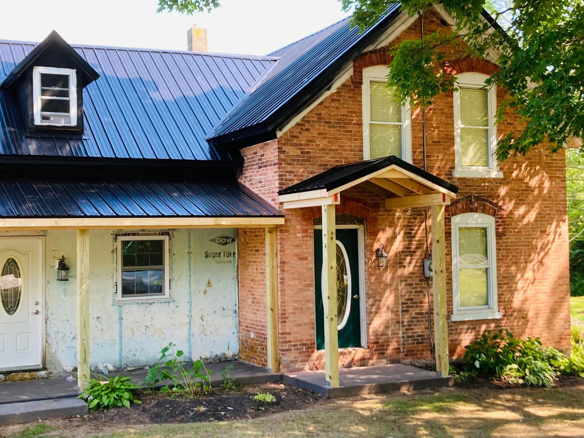 A brick house with a blue roof and a porch