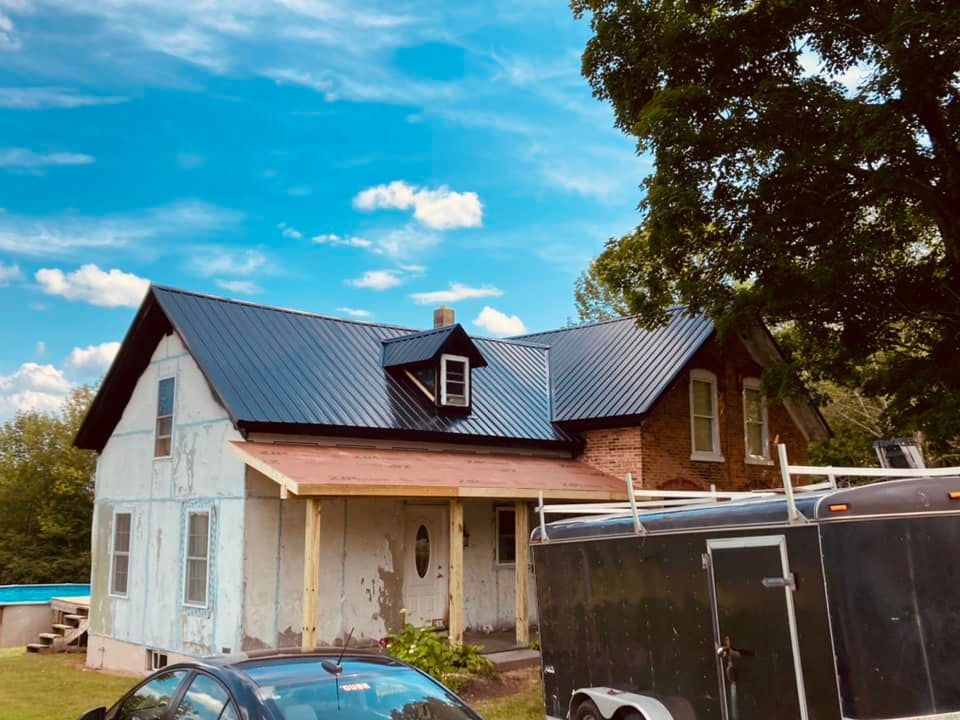 A car is parked in front of a house with a trailer attached to it.
