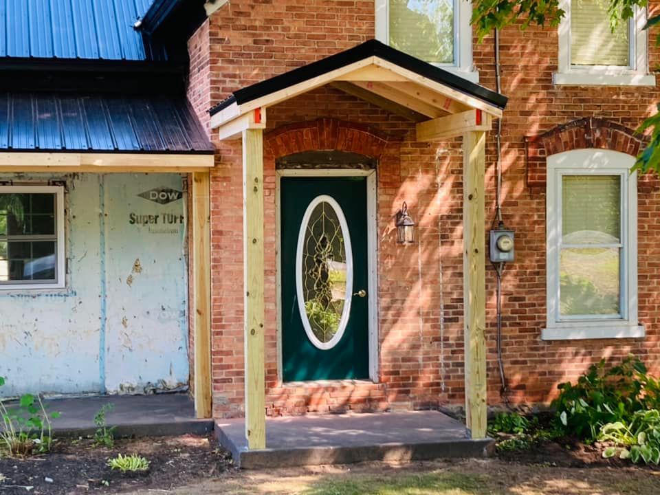 A brick house with a porch and a green door.