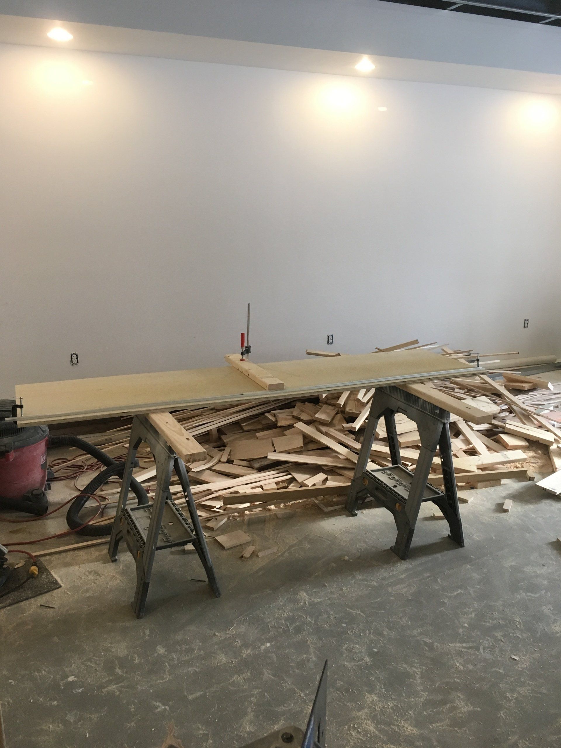 A wooden table is sitting on top of a pile of wood in a room under construction.