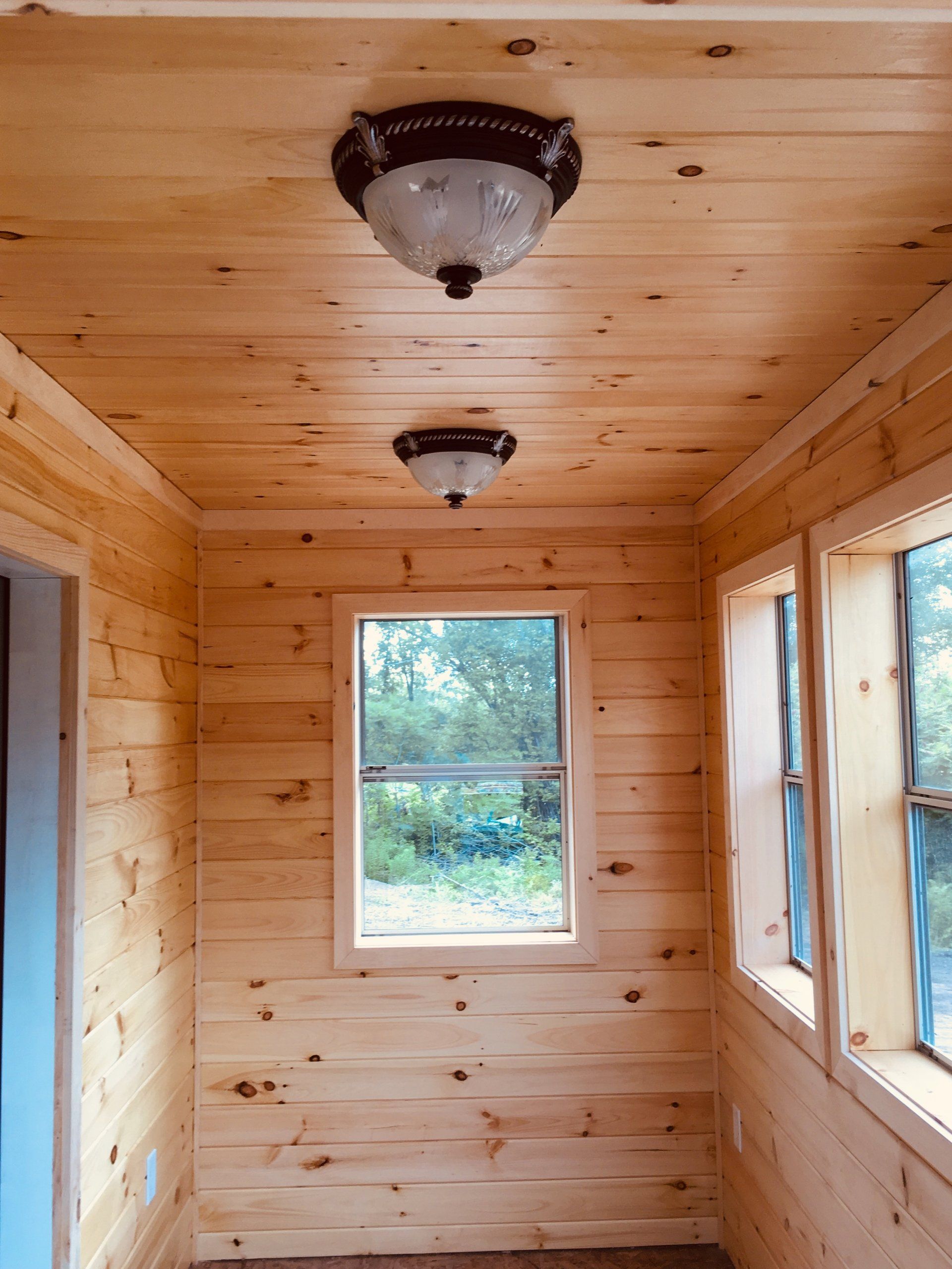 A wooden room with a ceiling light and a window.