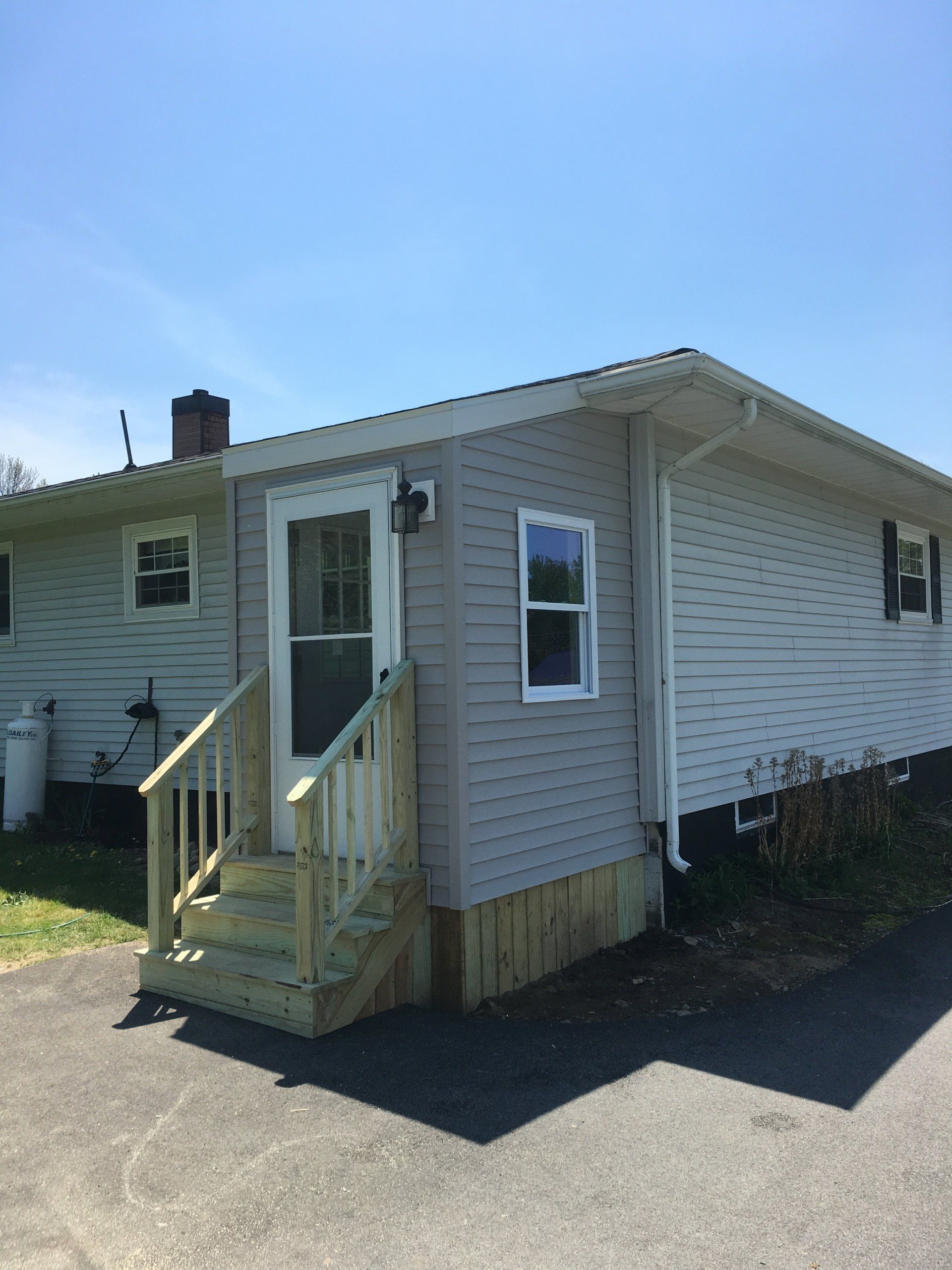 A small white house with stairs leading up to the front door.