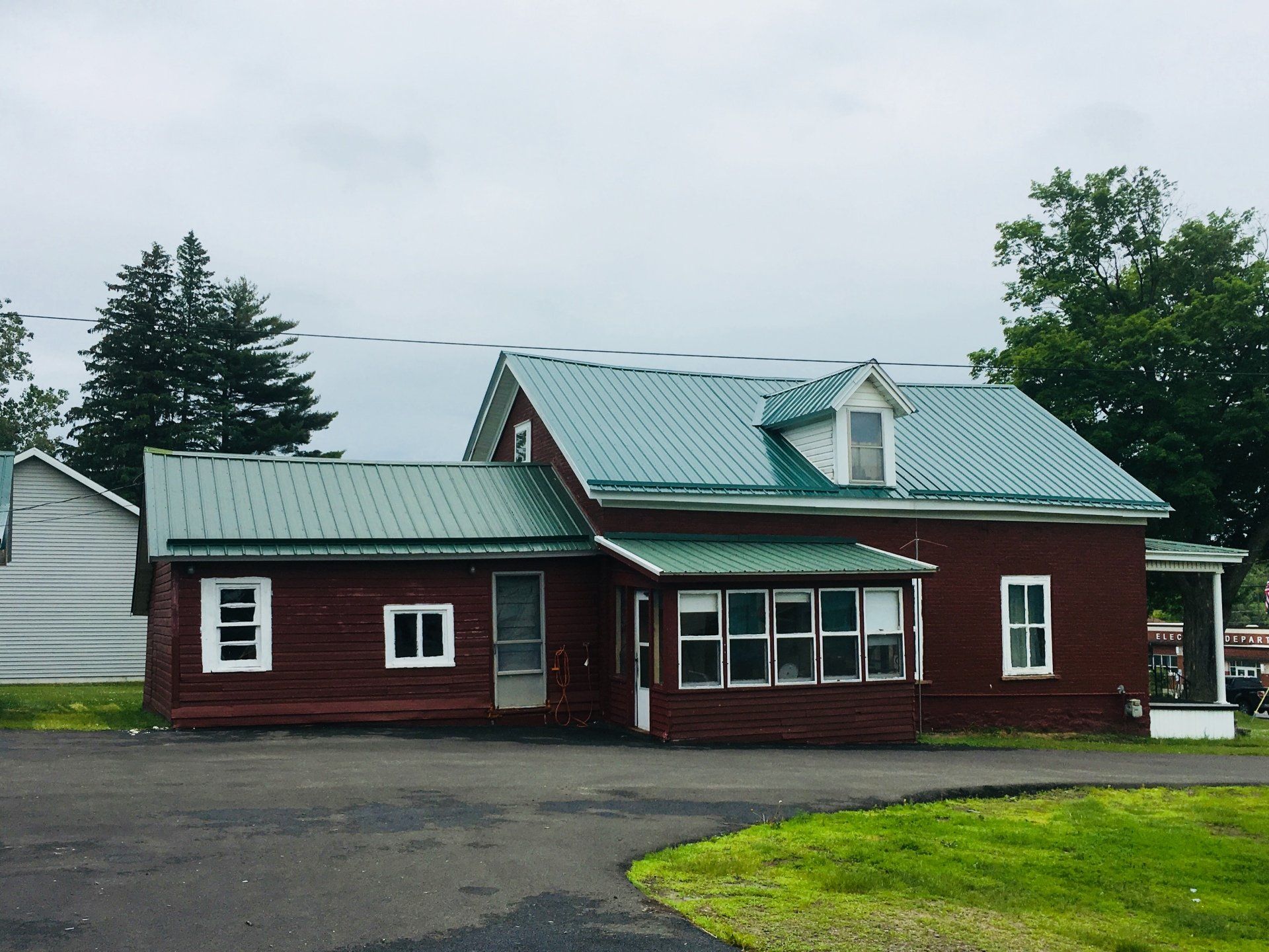 A red house with a green roof and white windows