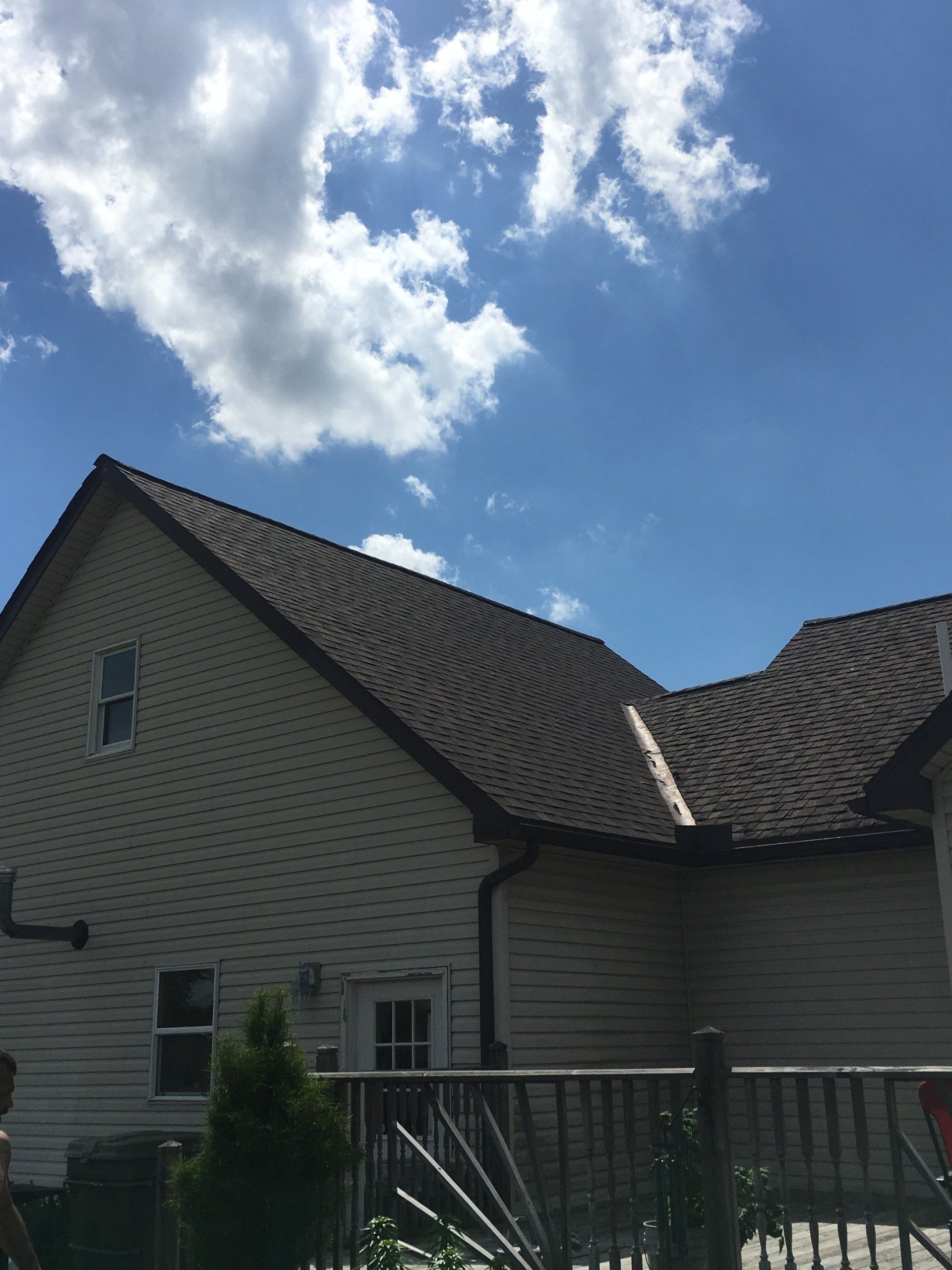 A white house with a brown roof and a blue sky with clouds