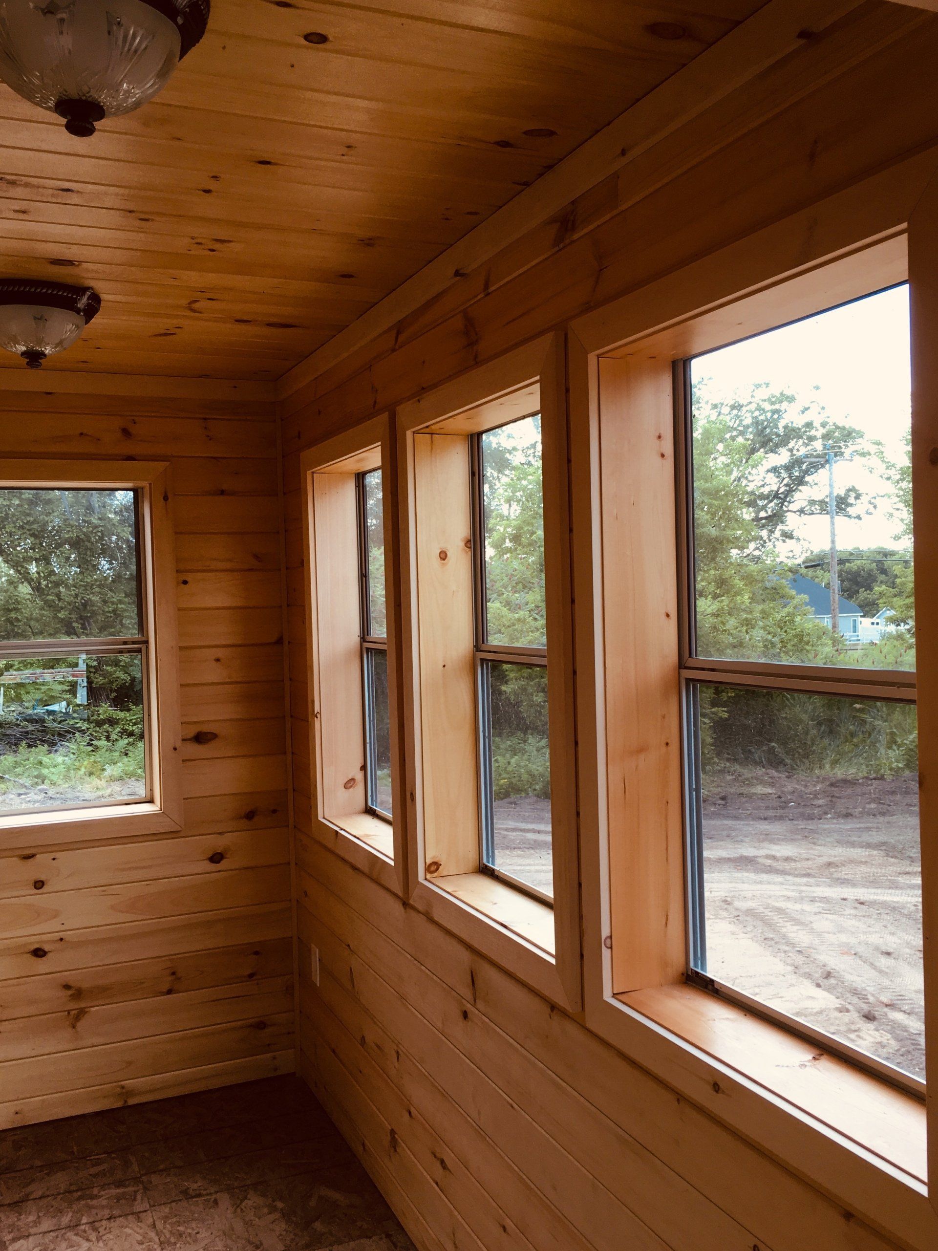 A wooden room with a lot of windows and a ceiling light.