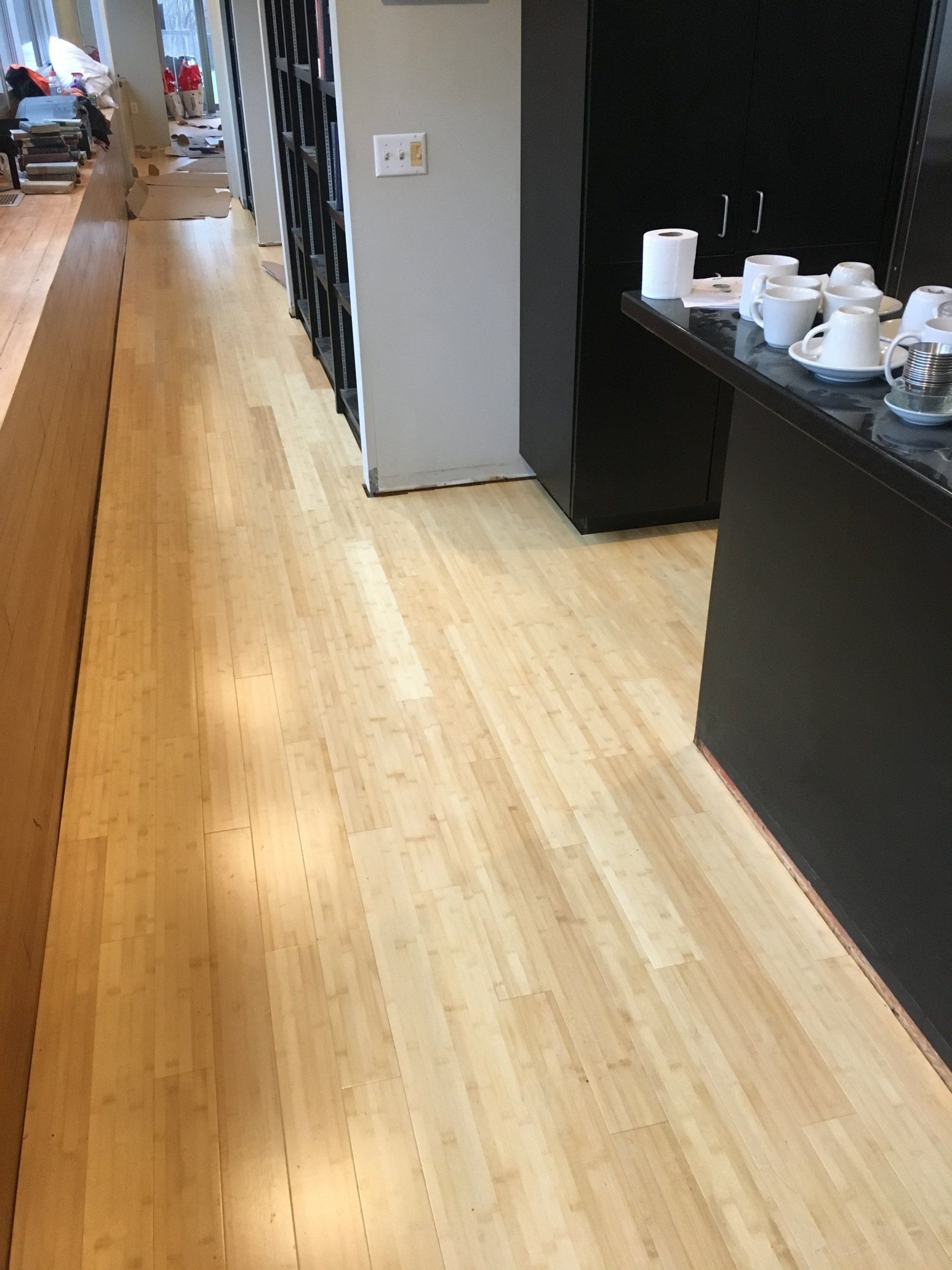 A long hallway with a wooden floor and a table with cups and saucers on it.