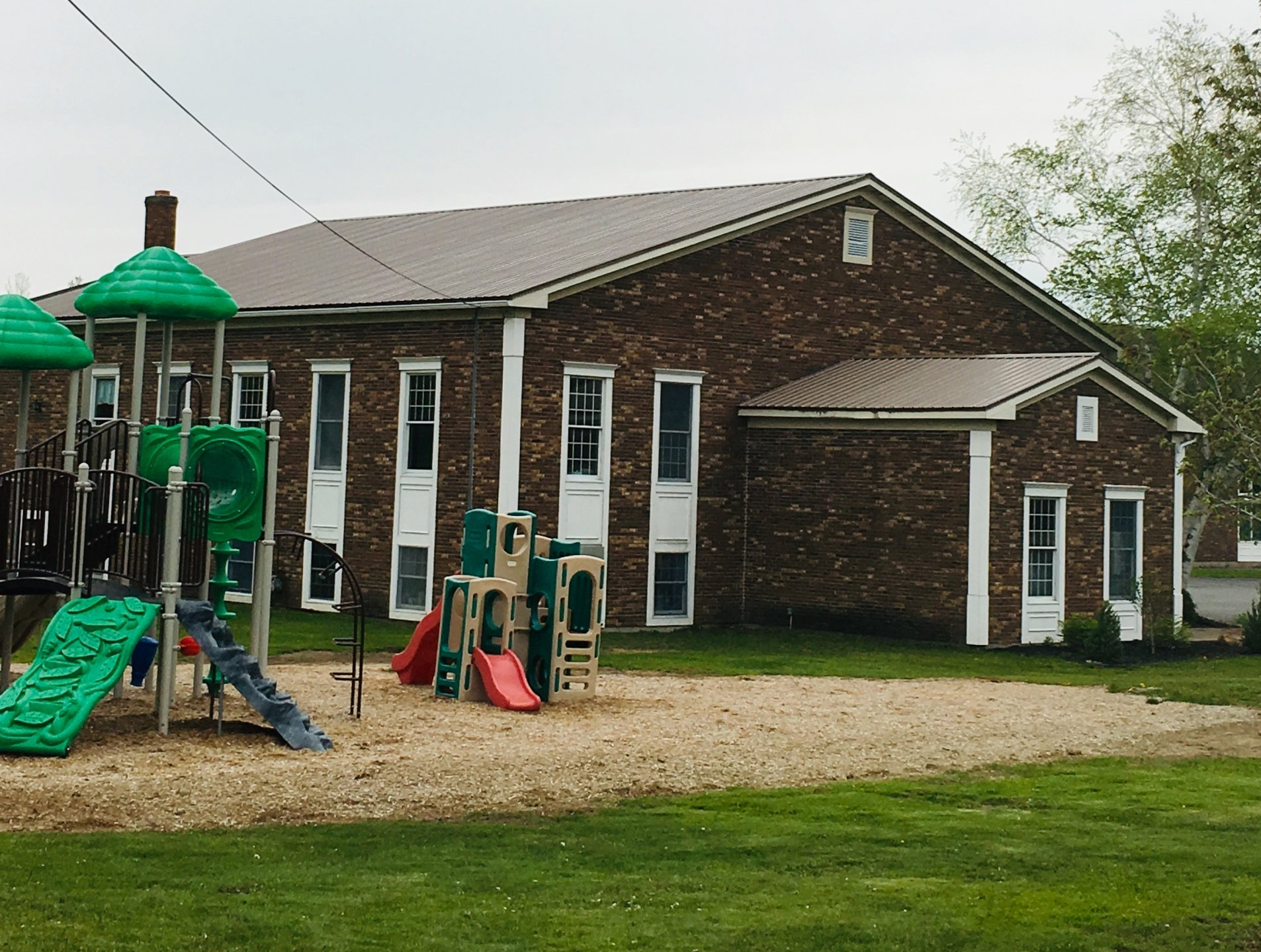 A brick building with a playground in front of it.