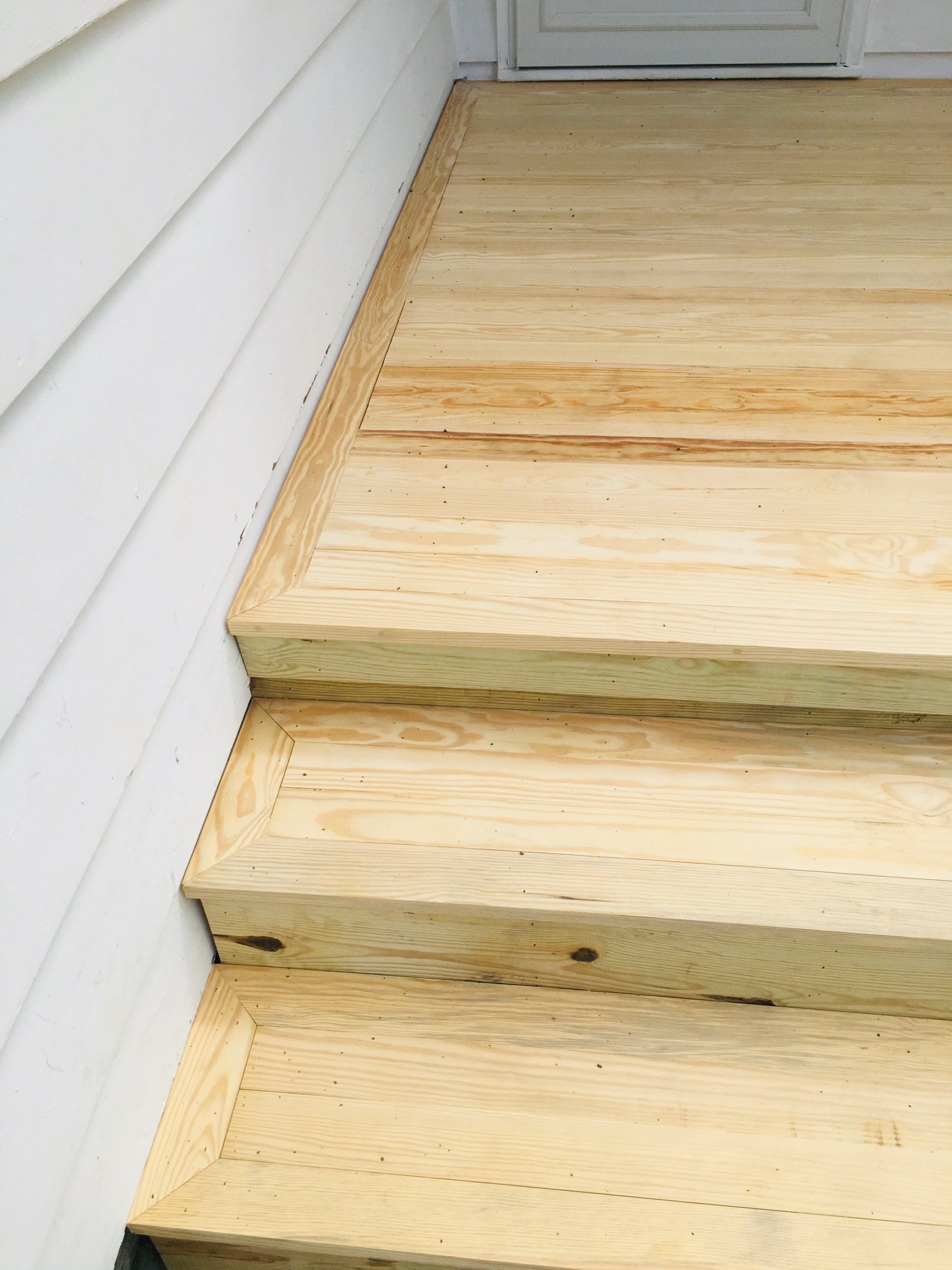 A set of wooden stairs leading up to a white door.
