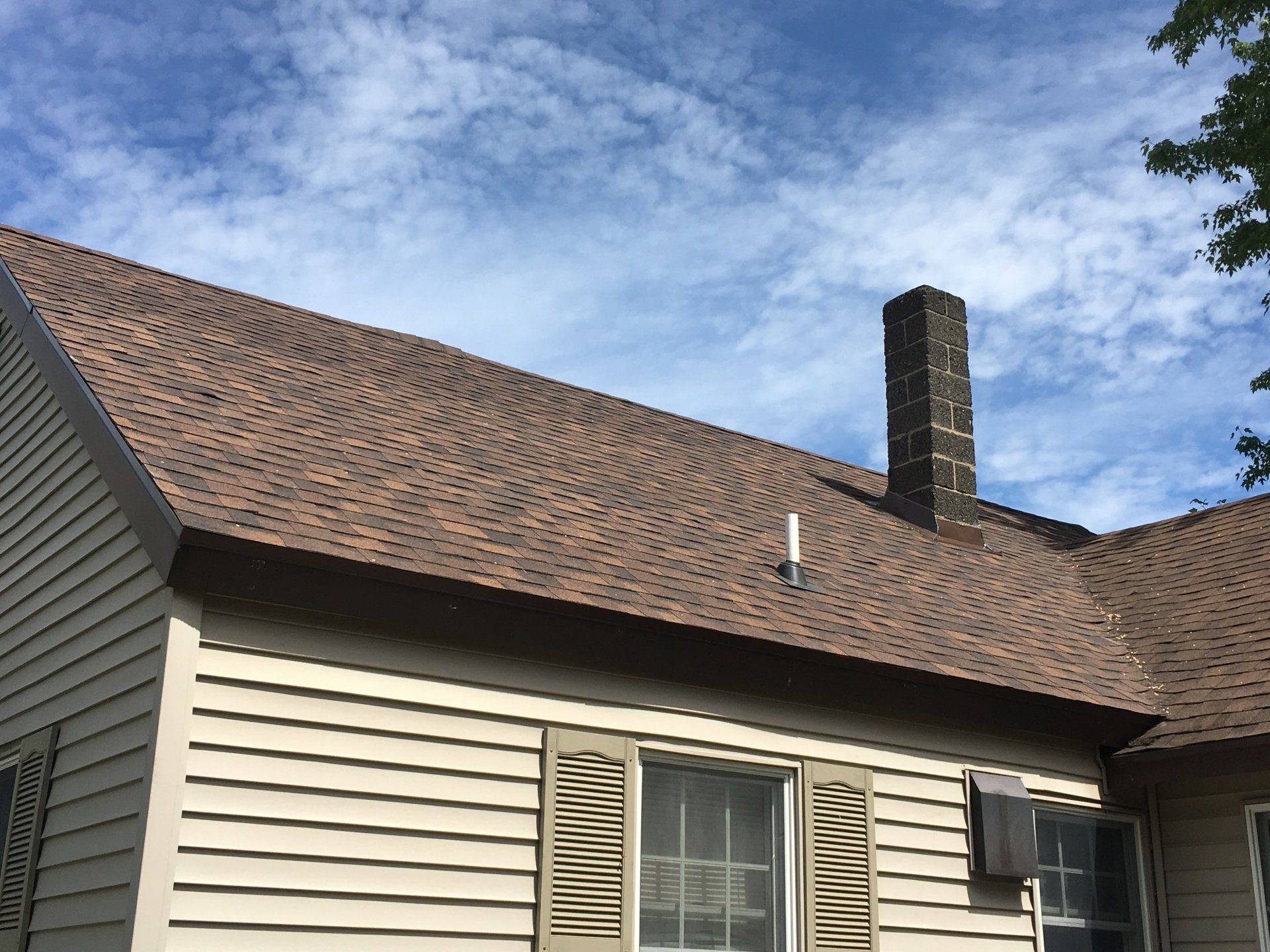 A house with a brown roof and a chimney on top of it.