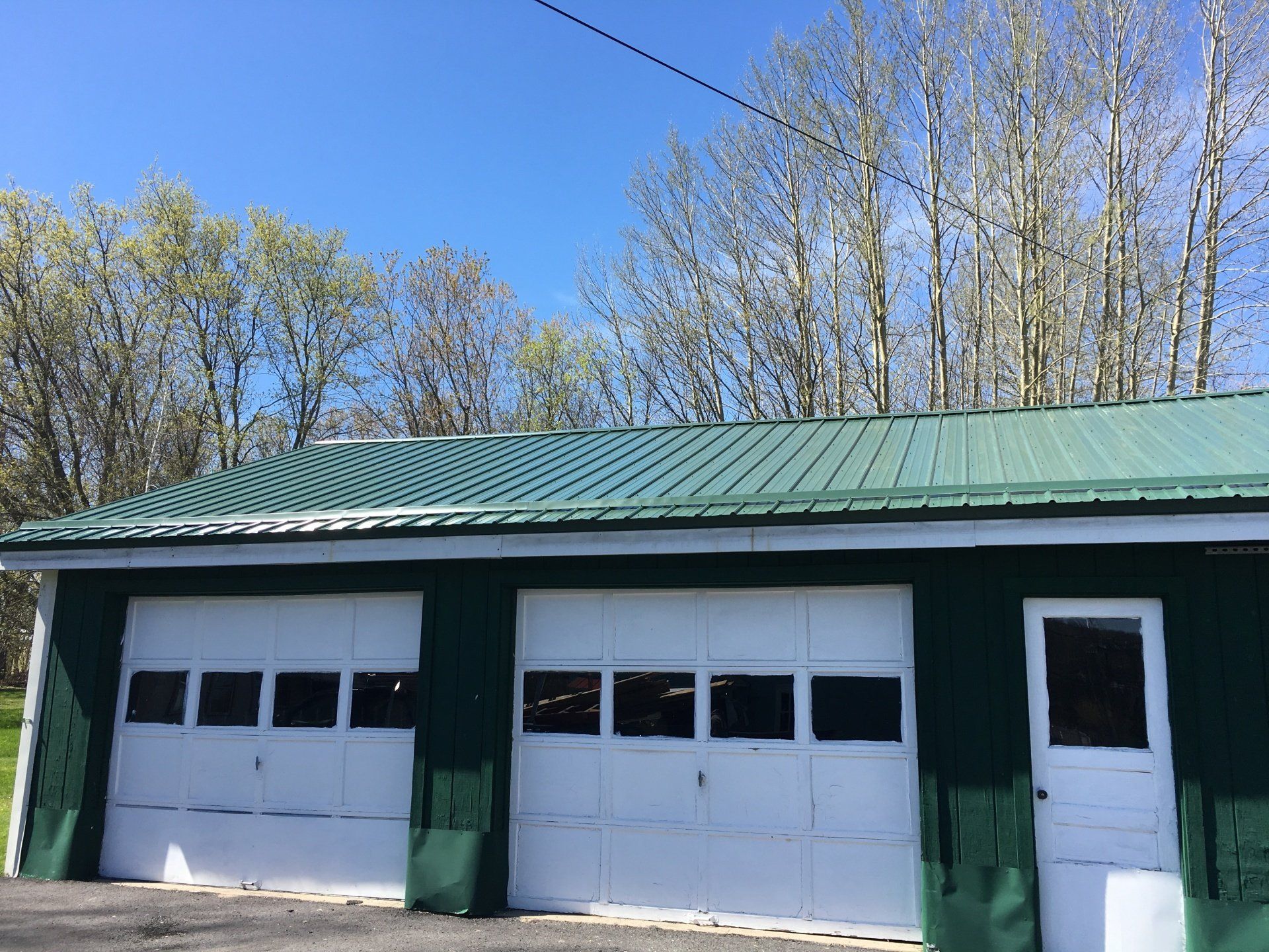 A green garage with white doors and a green roof