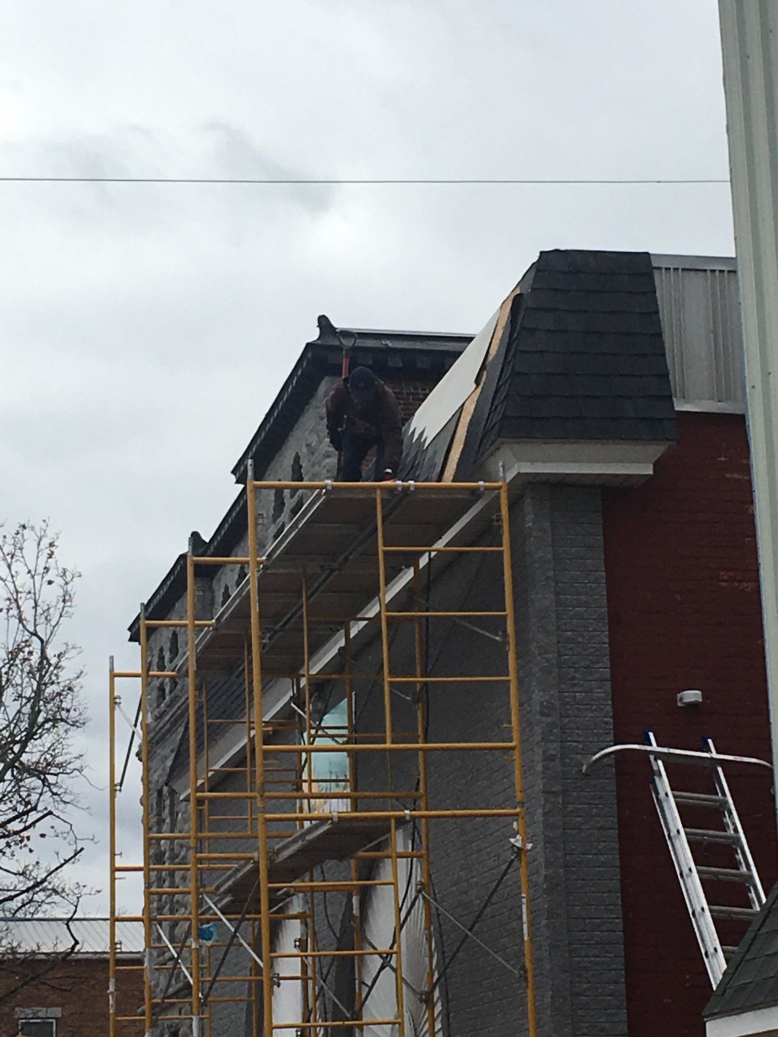 A man is standing on a scaffolding on top of a building.