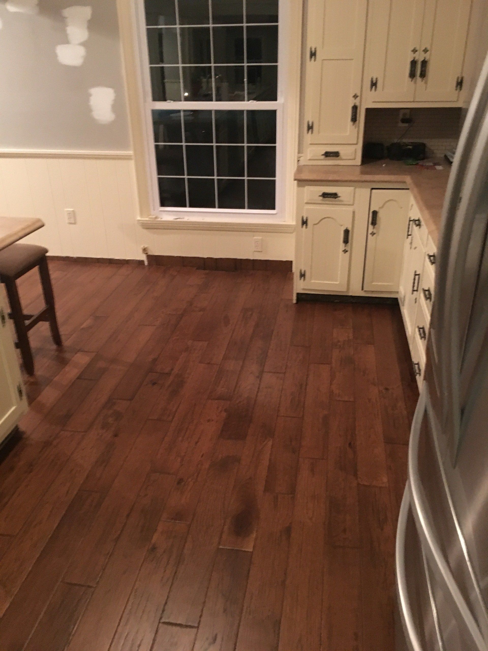 A kitchen with hardwood floors and white cabinets