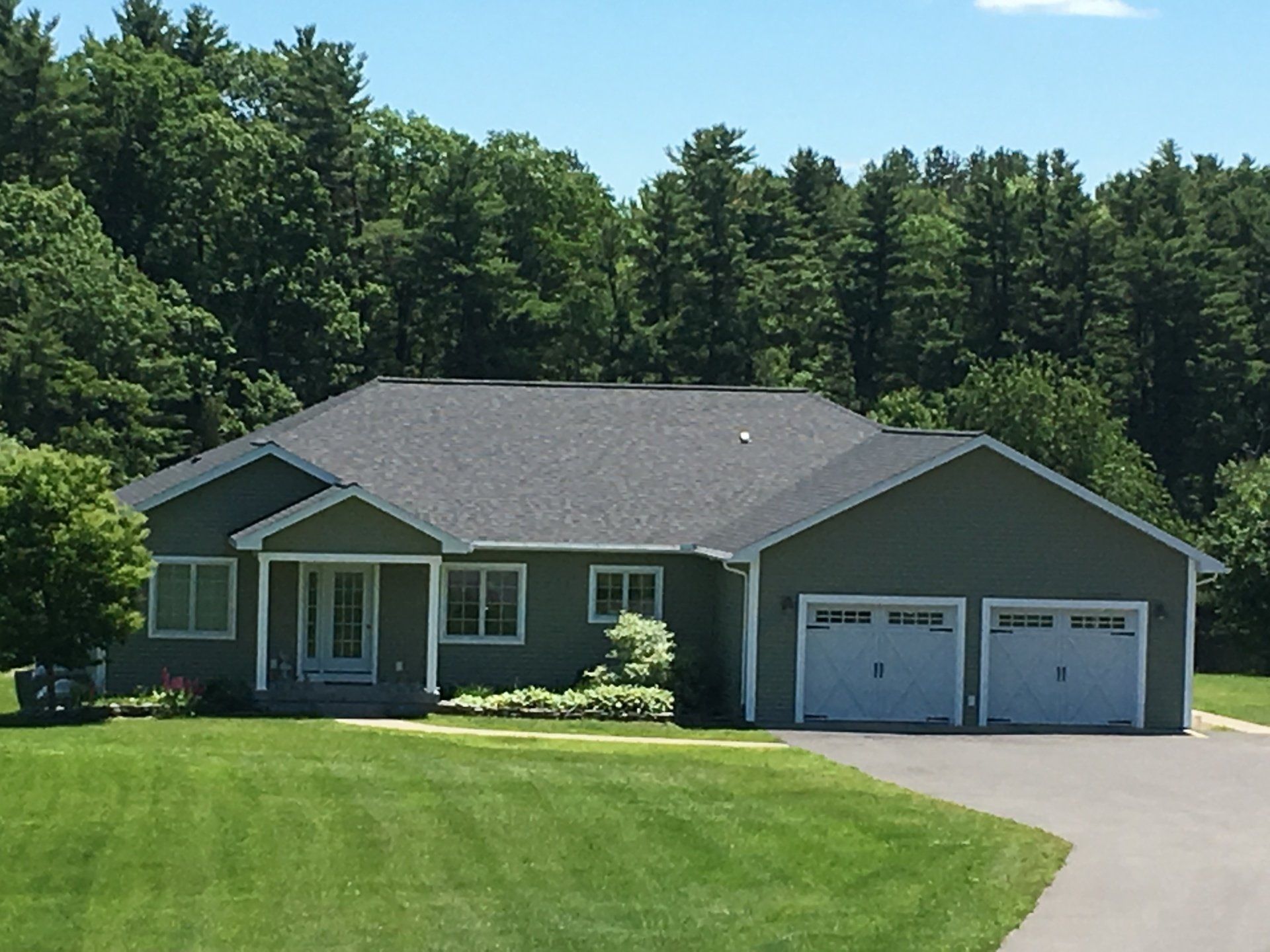 A house with two garage doors is surrounded by trees